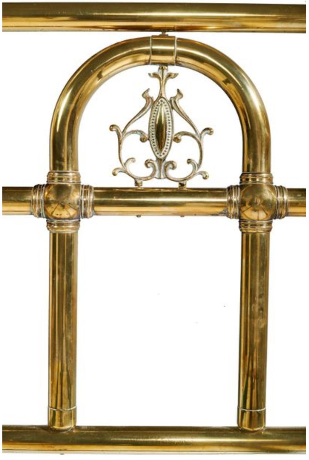 Early 20th century polished brass bed with large headboard and footboard with elegant details raised on original casters.
France, circa 1900.