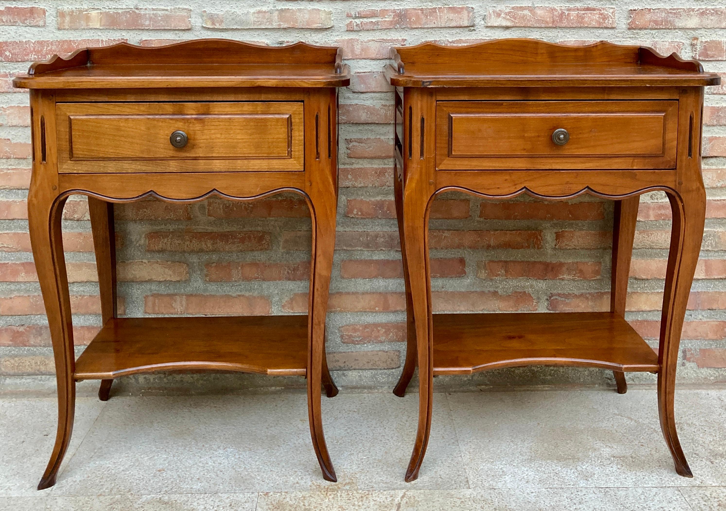 Pair of 20th century French bedside tables with a drawer, a low shelf and cabriolet legs. The tables have beautiful carving on the legs and sides and skirting on the front. They also have a low shelf on top and a ridge around their lid. 
Very nice