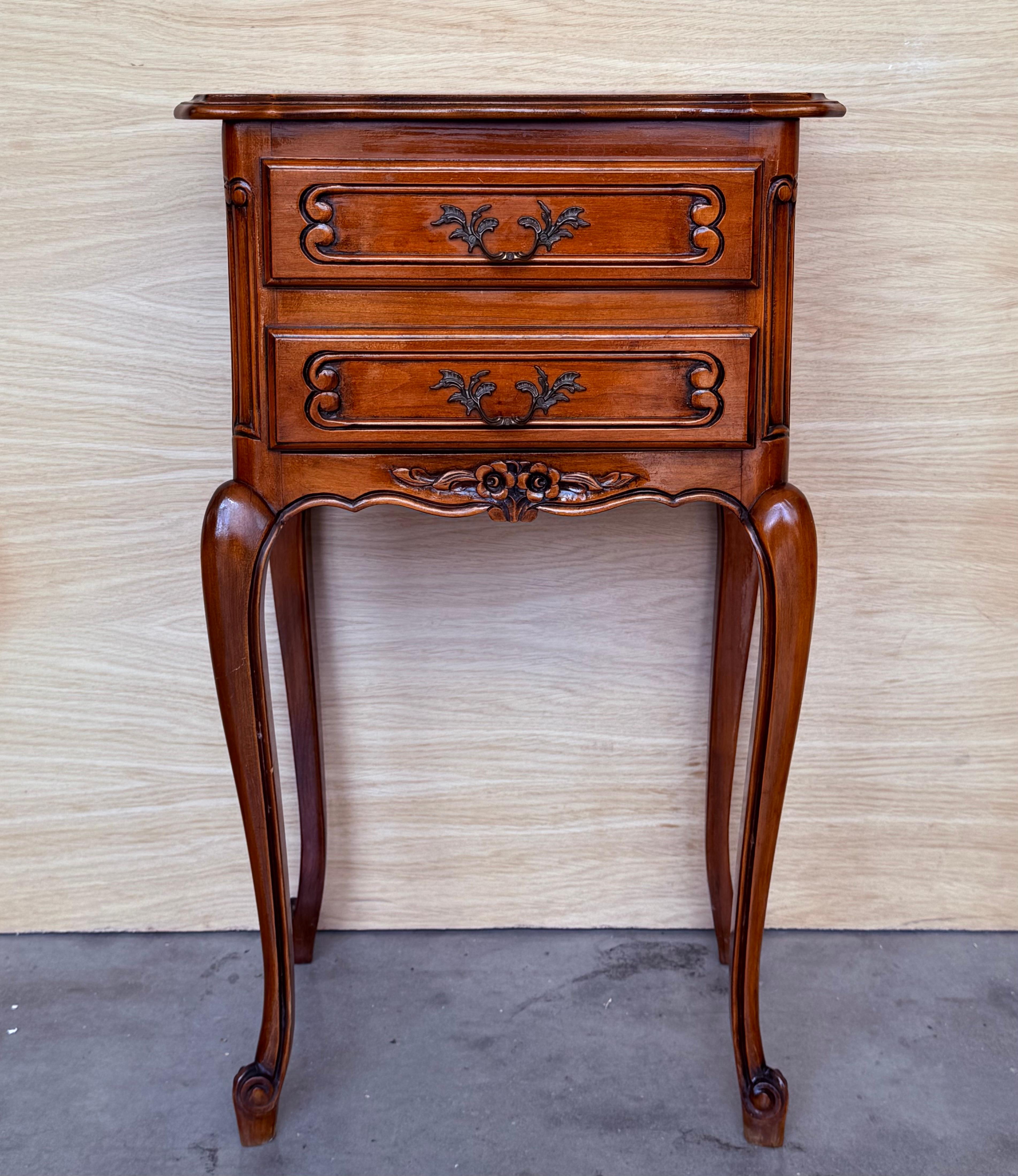 A fine pair of French bedside end tables or nightstands - each Stand featuring a scalloped edge gallery over a frieze of two drawers with brass pulls, apron bottom, and set upon four tapering cabriole legs.