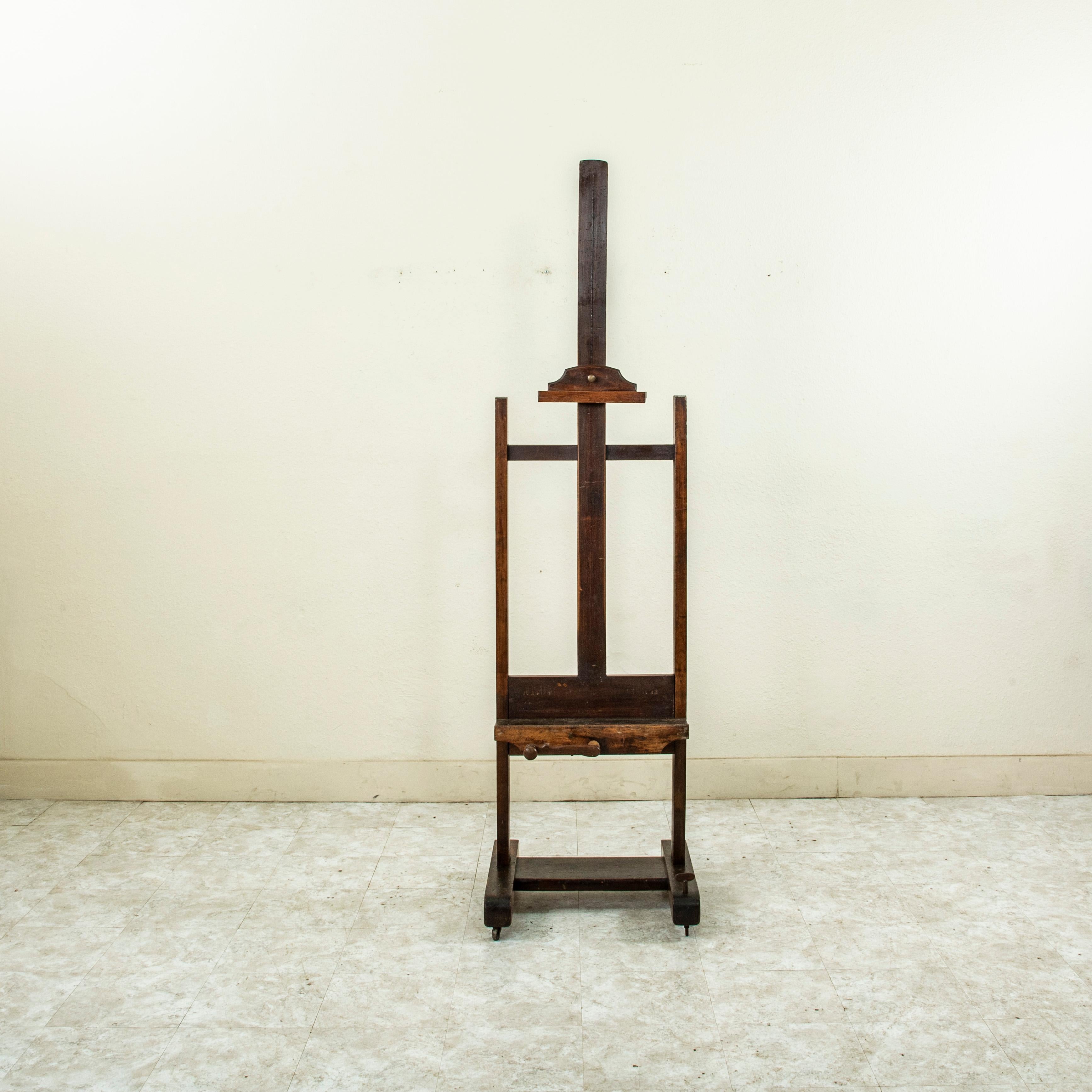 Ce chevalet d'artiste en bois de hêtre français du début du XXe siècle est doté d'un mécanisme à manivelle en bois qui permet de régler la hauteur de 69,5 à 105 pouces. Son plateau d'une profondeur de 4,25 pouces permet d'accueillir des toiles plus
