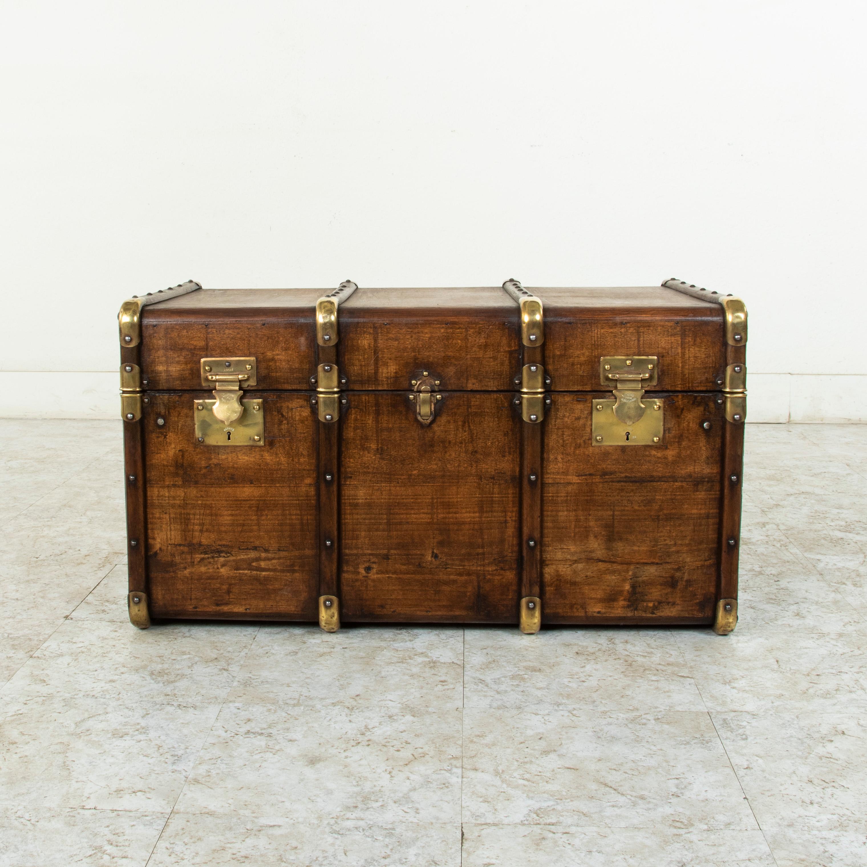 This French beech wood steam trunk from the turn of the twentieth century features wooden runners detailed with brass rivets. Its brass caps at the corners offered protection from damage when traveling, and its original leather handles are still