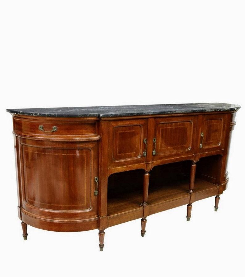 An elegant French Belle Époque period mahogany sideboard dating to the early 20th century, hand-crafted in luxurious Louis XVI taste, featuring a stunning, dramatically veined white and black marble top, over solid wooden demilune shaped case
