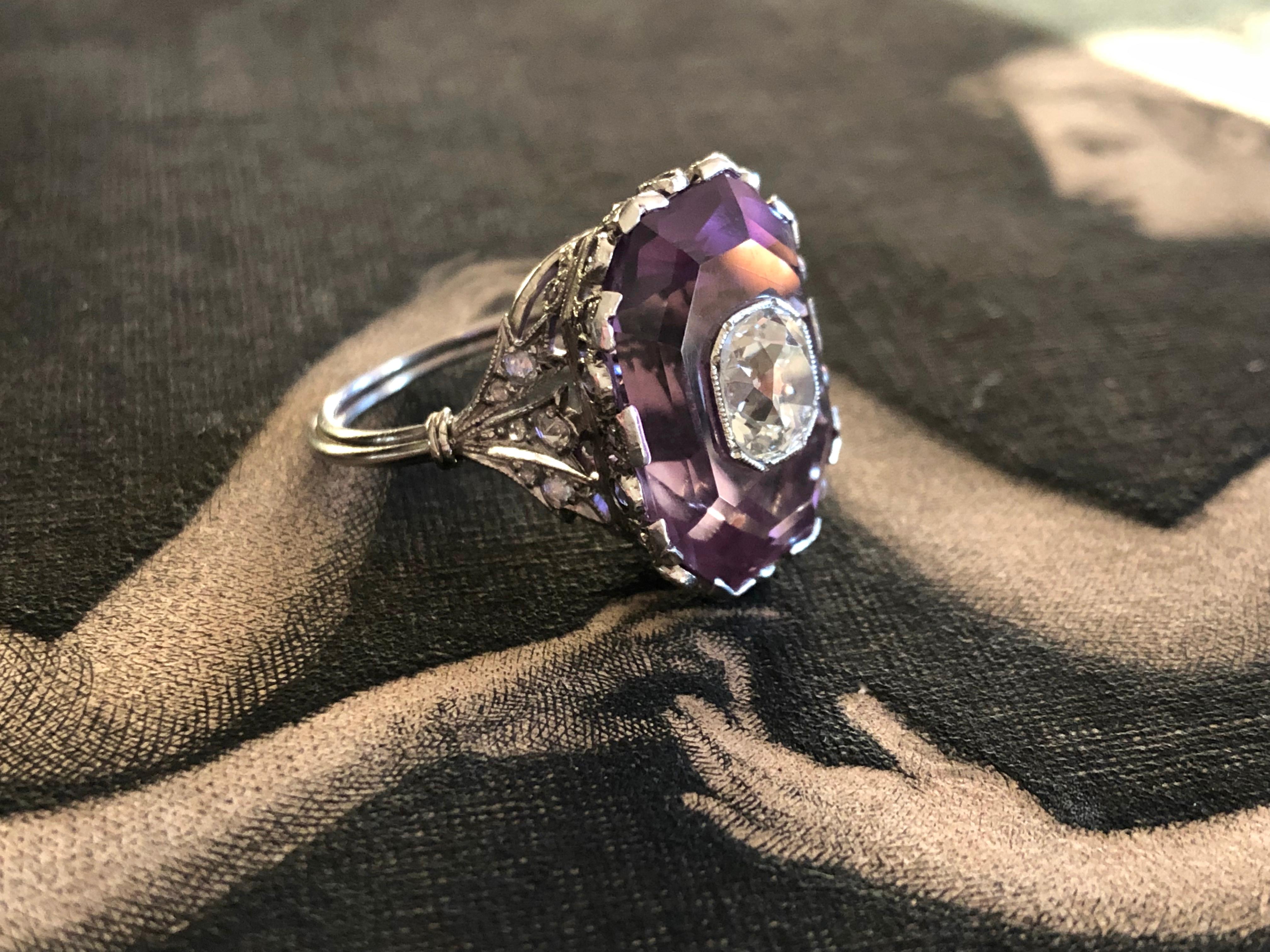 Exquisite in every way, this French Belle Epoque ring centers on 1.03 carat old mine cut diamond, bezel set and seated within an octagonal step cut amethyst. The mounting is like a tiny crown, delicately detailed with lacy openwork and twinkling