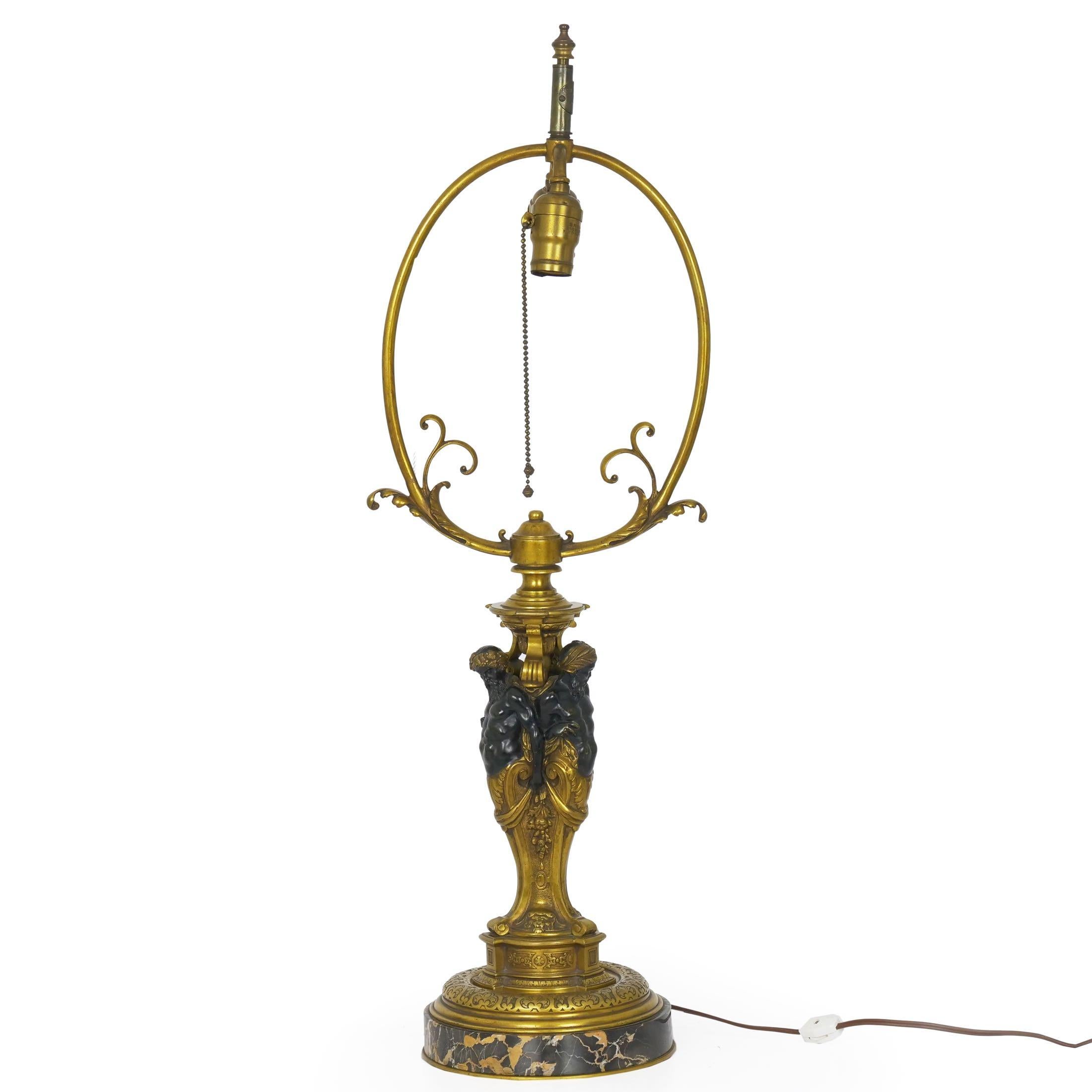 An inordinately fine cast bronze table lamp, the piece features three male figures that rise from a cabriole stem of acanthus. Each figure is unique, so while all are looking slightly leftward they each are captured with subtle variations; for