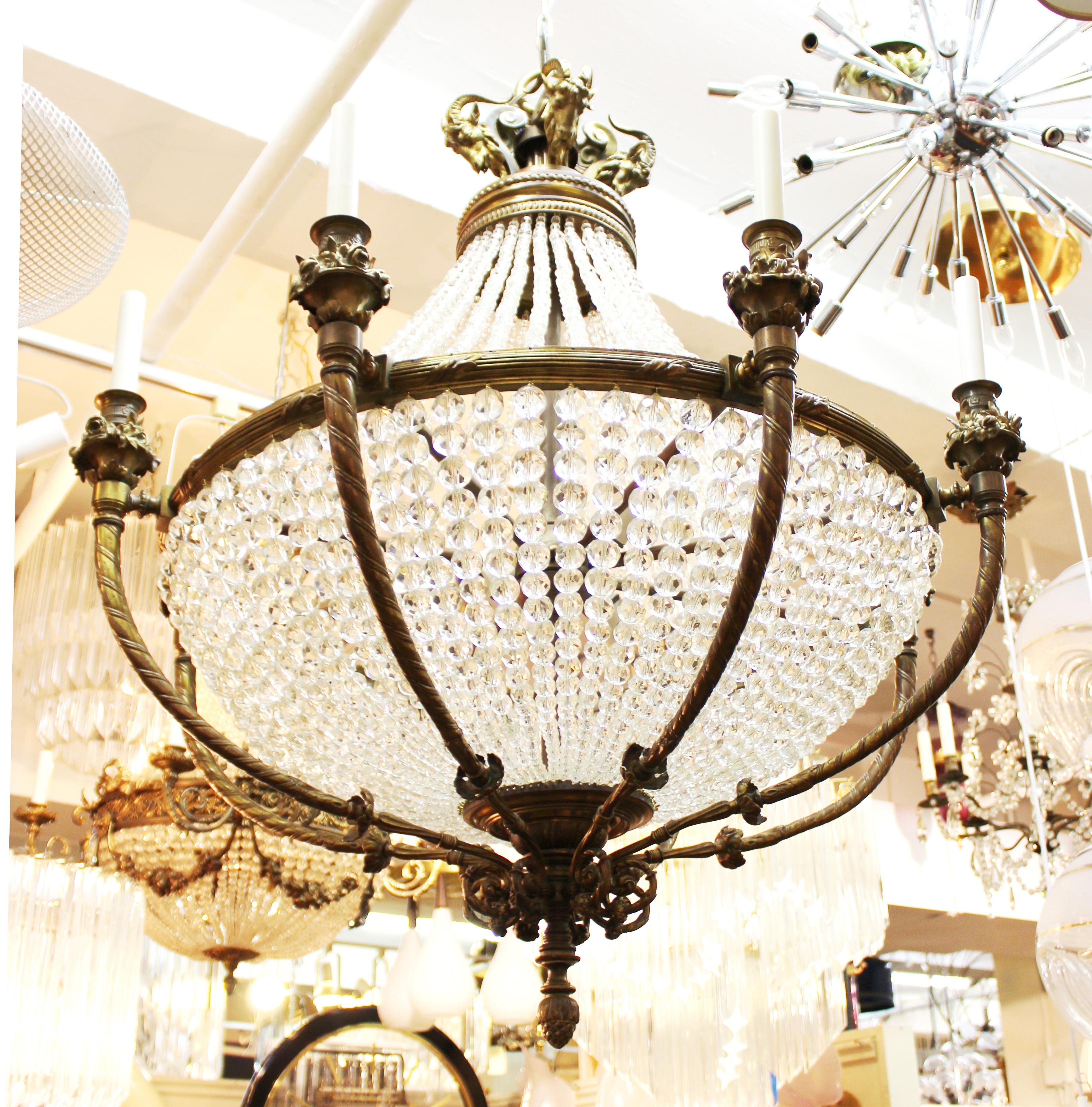 French Belle Époque monumental chandelier in bronze with crystal strands and ram's head embellishments. The piece was likely made during the 1890s in France and is in great vintage condition with age-appropriate wear.