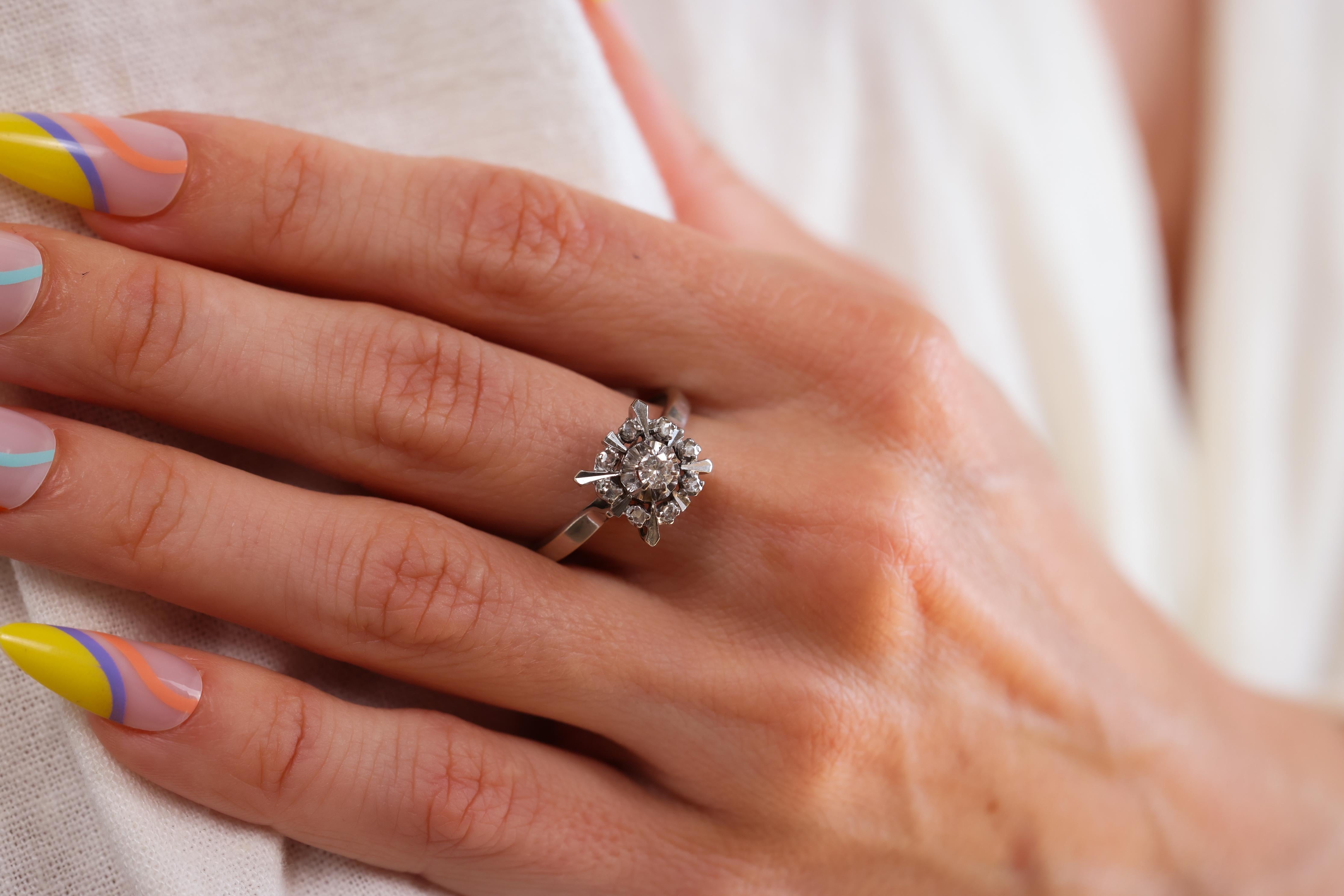 Center Stone: Diamond
Cut: Old European 
Weight: Approximately 0.15 Carats
Color: G
Clarity: VS
Accent Stone: 8 Diamonds 
Cut: Rose Cut
Weight: Approximately 0.08 Carats
Color: G
Clarity: SI
Metal: 18k White Gold
Era: Victorian 
Circa: