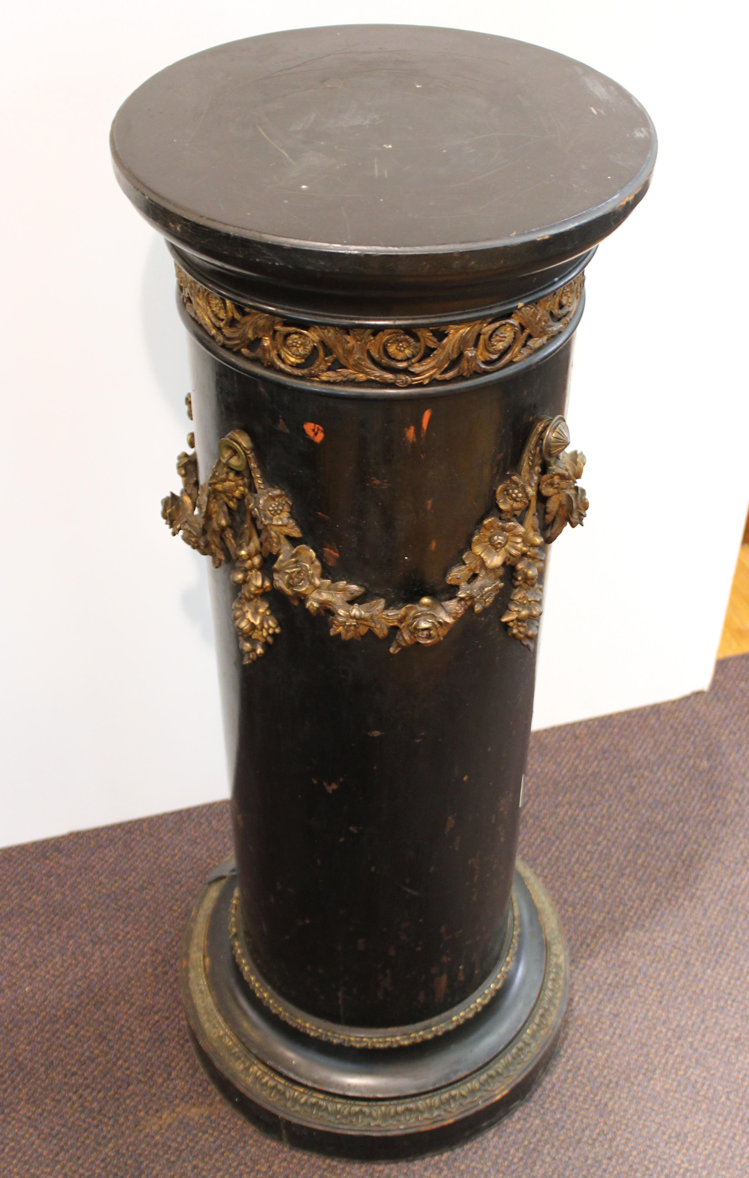French Belle Époque column or pedestal in ebonized wood, with decorative ormolu floral garlands and friezes on the base and top. The piece was made in France during the 1890s and is in great vintage condition with age-appropriate wear.