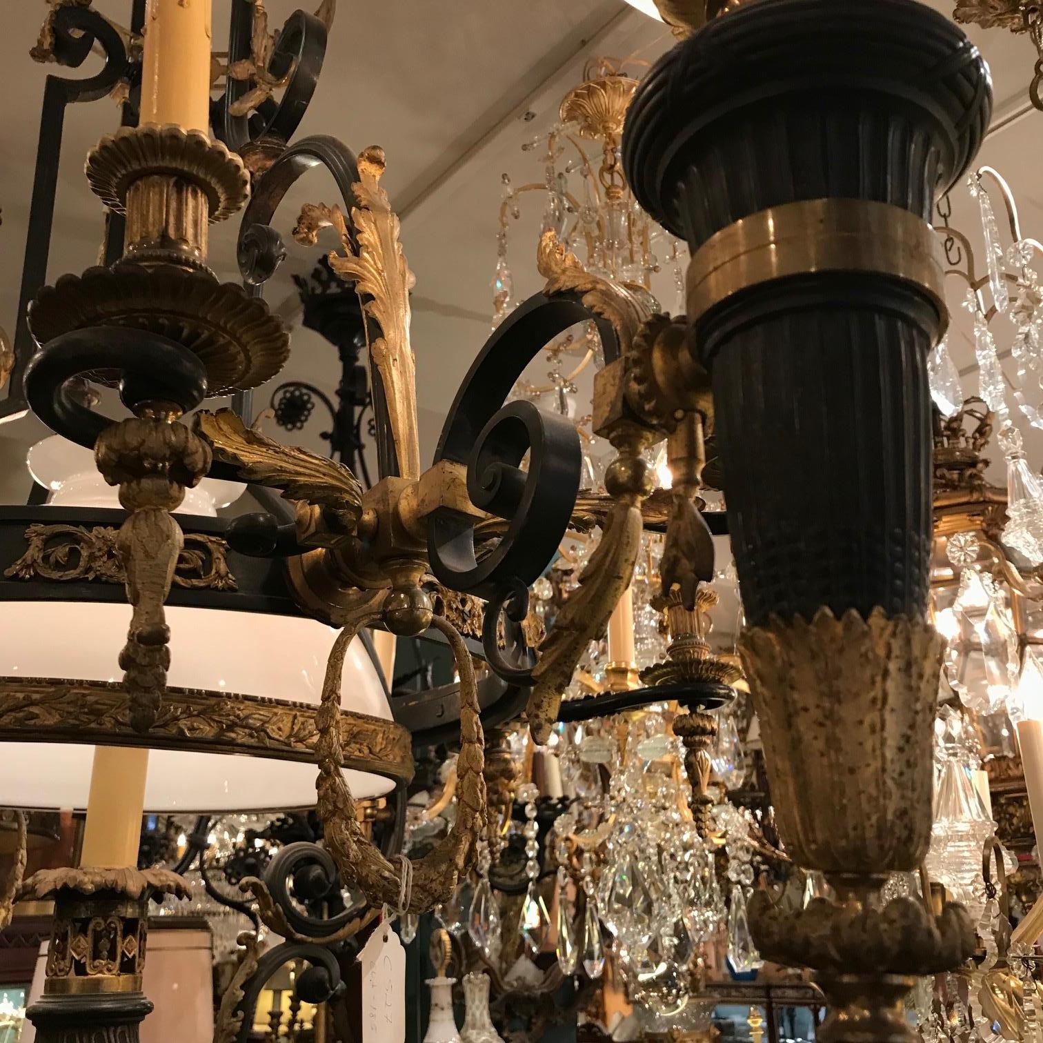 This most unusual fixture was once gas and oil and has been subsequently electrified. It has a pair of globe shades mounted on oil reservoirs  flanking a central light , it also has eight lights once gas and now electric .  The bronze frame is