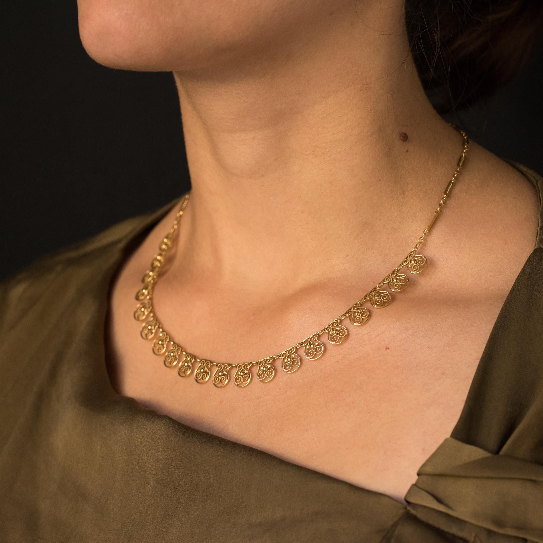 Necklace in 18 karats yellow gold, eagle's head hallmark.
Lovely antique necklace, it consists of 20 openwork patterns, filigree and each adorned with a pearl of gold. The patterns are retained by an alternating oval mesh chain of rectangular