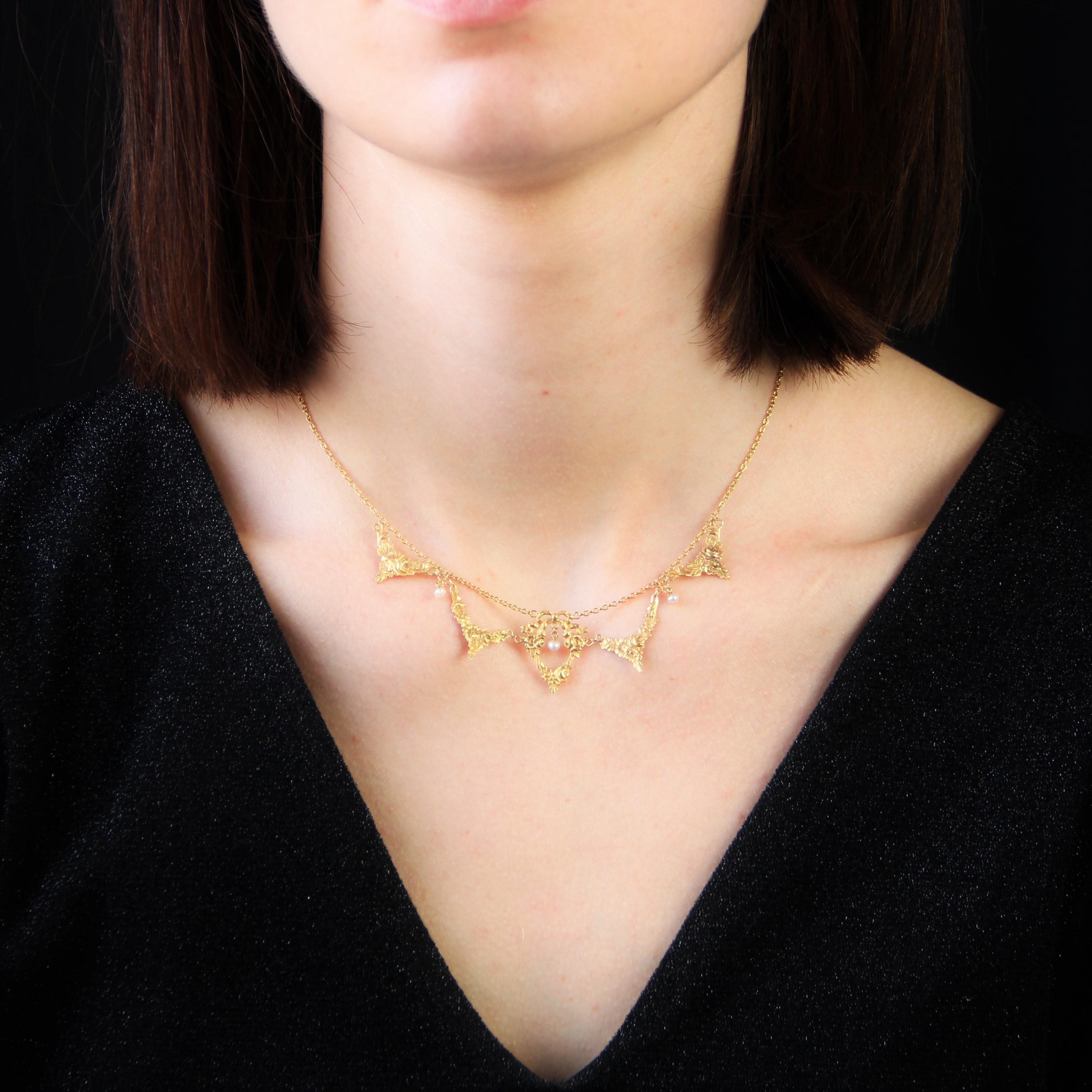 Necklace in 18 karat yellow gold, eagle head hallmark.
Antique necklace, called drapery, it is formed of a thin convict mesh chain holding on the front 5 patterns, engraved with floral decorations, knots and garlands. 3 small pearly white baroque