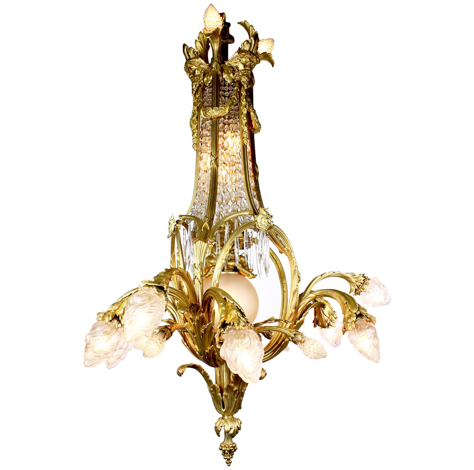 A large and rare French Belle Époque gilt bronze and cut-glass twenty-four light figural chandelier. The elongated gilt bronze frame with scrolled floral arms protruding from the lower section with frosted glass shades and beaded glass bulb covers;