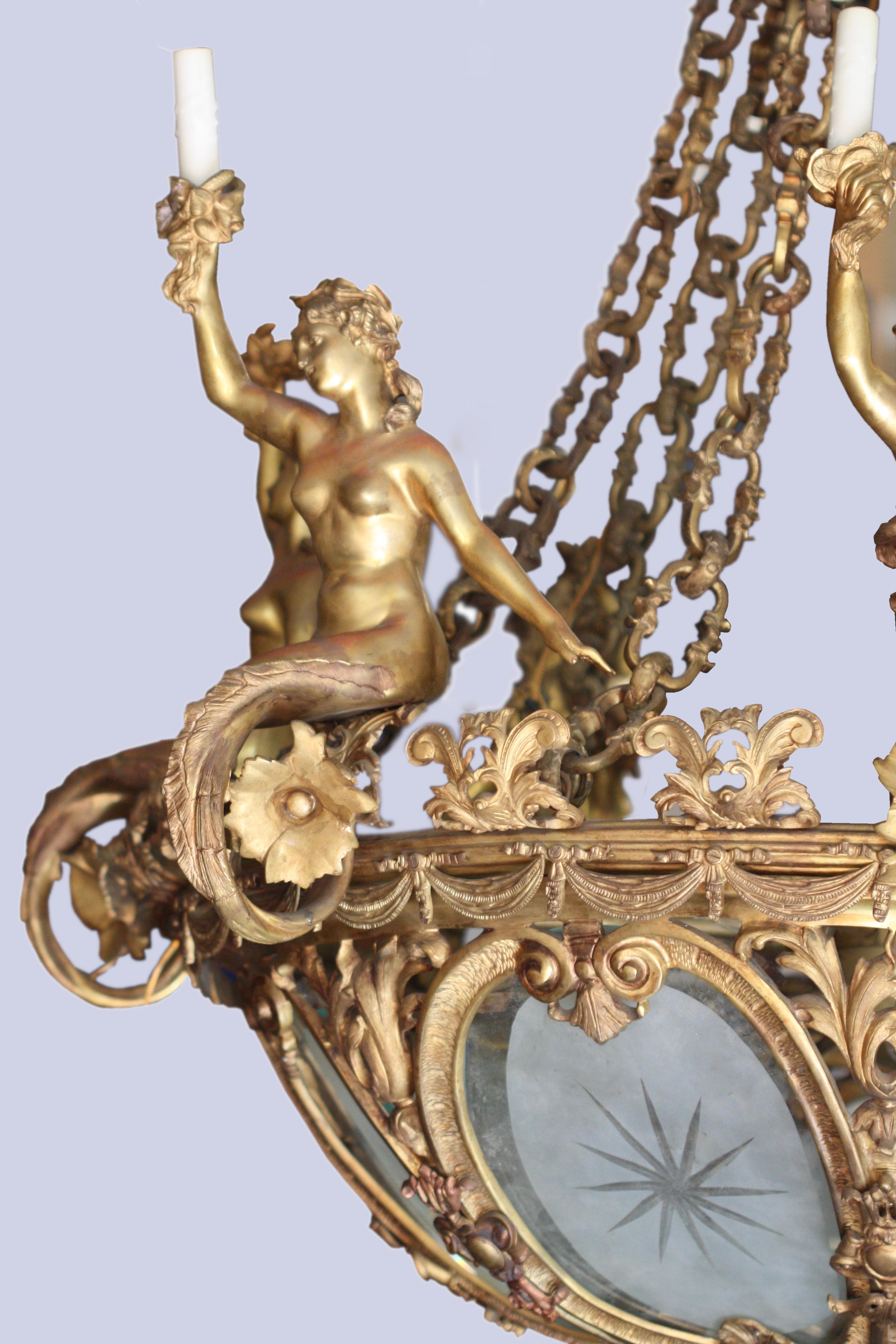 A French Belle Époque gilt bronze chandelier 
late 19th century.
The corona surmounted by stylized foliate motifs, suspending an etched glass bowl within a C-scroll pierced frame, topped with acanthus leaf finials interspersed with mermaids holding