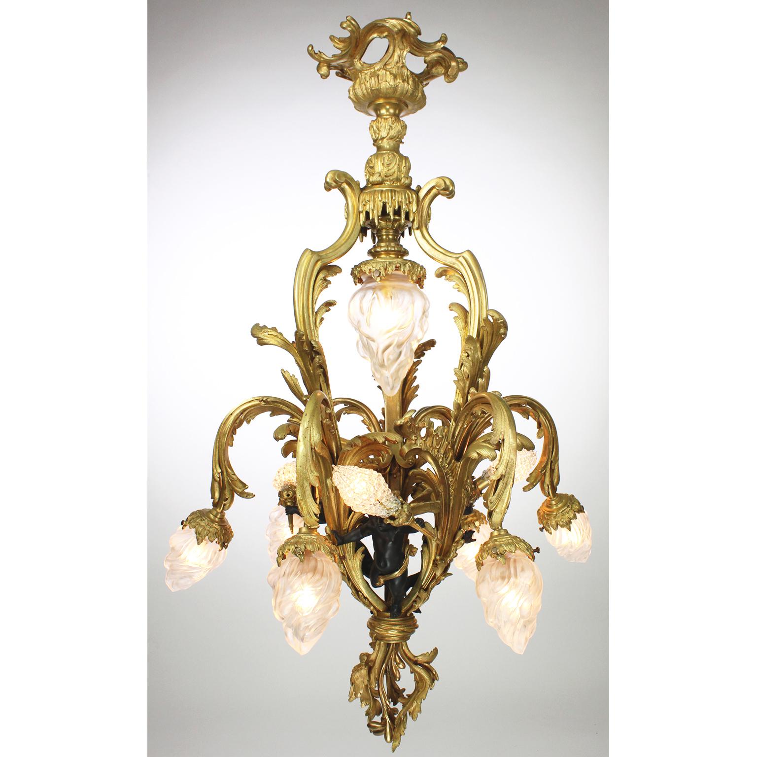 A very fine and rare French Belle Époque gilt bronze and ebonized-patinated bronze ten-light figural chandelier, with three winged cherubs, each holding a flame light with beaded glass bulb covers, the six outer lights with frosted glass flame