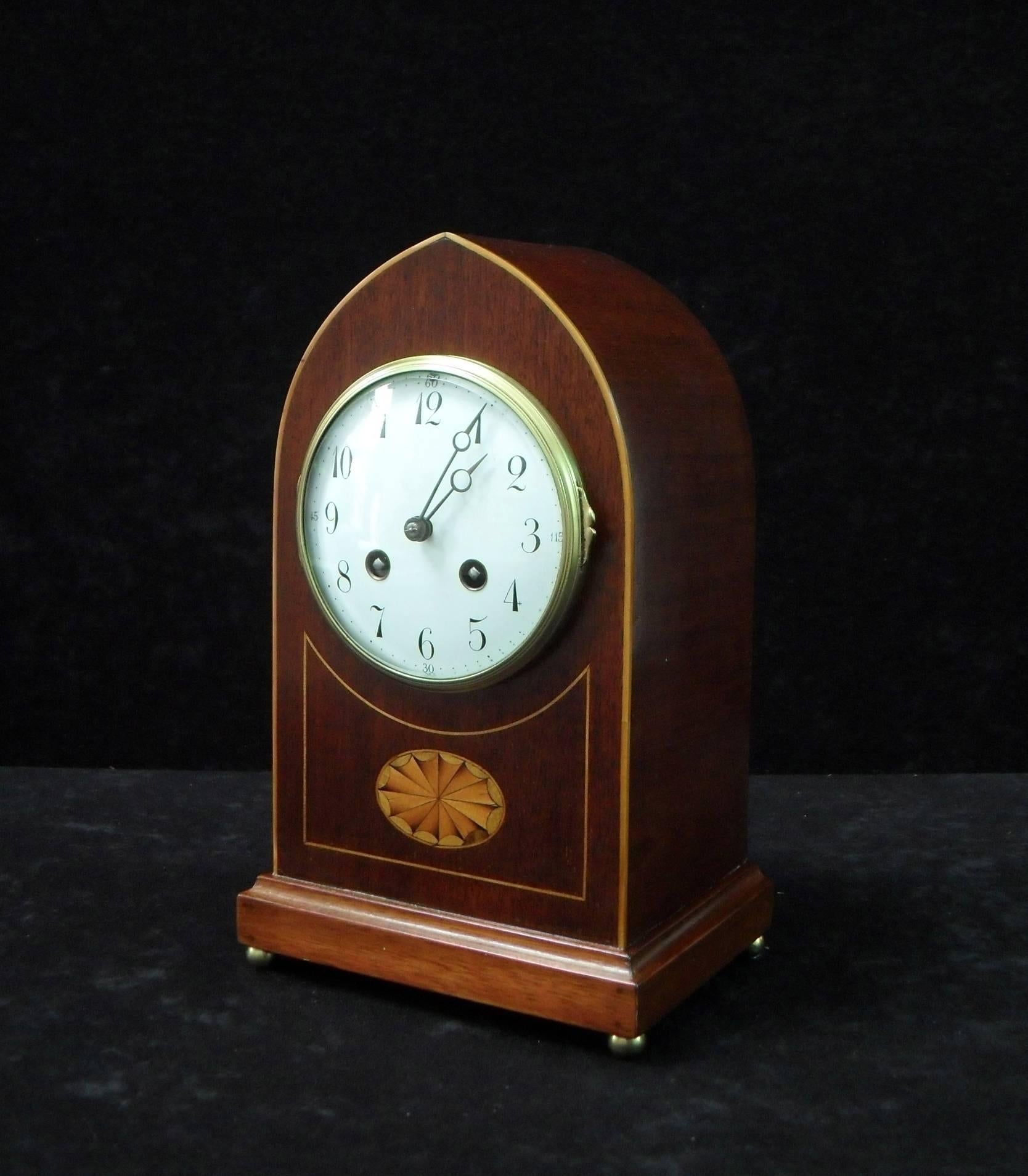 A good quality Belle Époque mahogany lancet top mantel clock with fan inlay and boxwood stringing to the front of the case. The clock has a white enamel dial with a French eight day movement which strikes the hours and half hours on a gong.

The