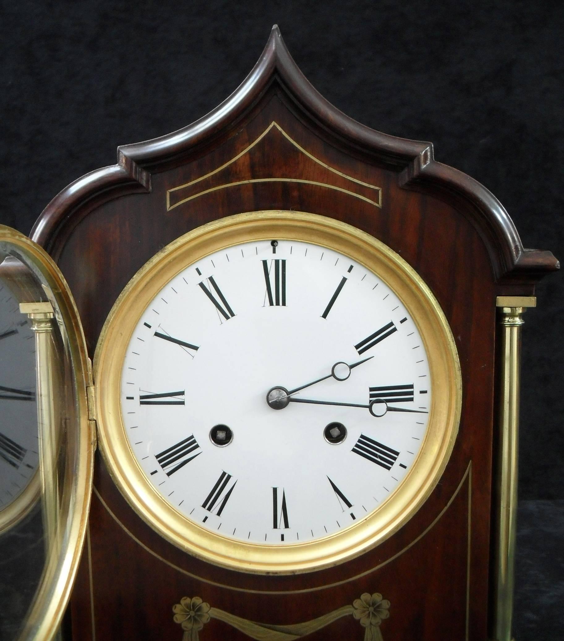 A very good quality French figured mahogany Belle Époque mantel clock with brass inlay and brass columns to the front and architectural shaped top. The clock has a white enamel dial with a French eight day movement which strikes the hours and half
