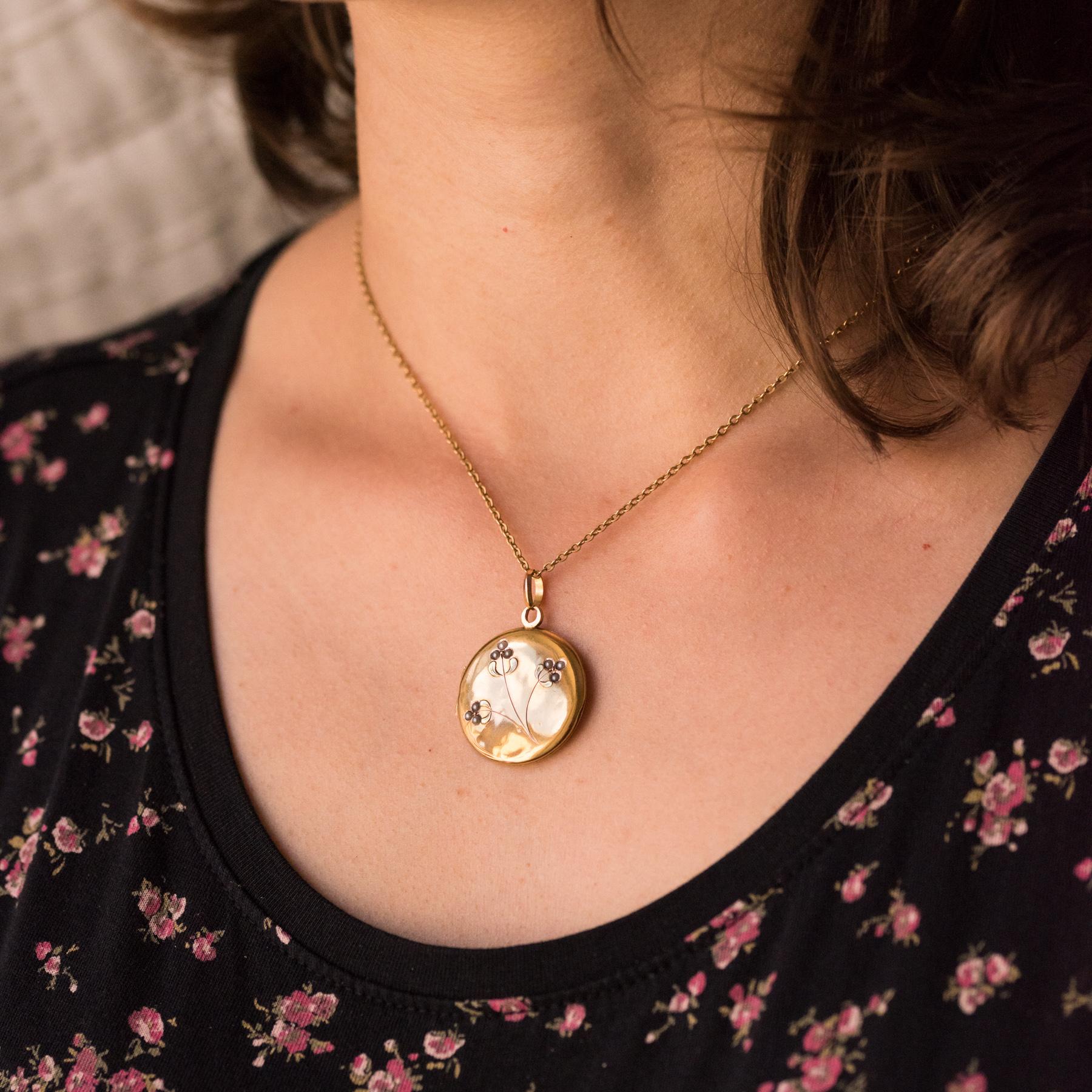 Medallion in 18 karats yellow gold, eagle's head hallmark.
Round, this charming antique pendant has two smooth faces whose the top one is delicately set with natural half-pearls represented flowers chiseled plants. This antique jewel opens with a