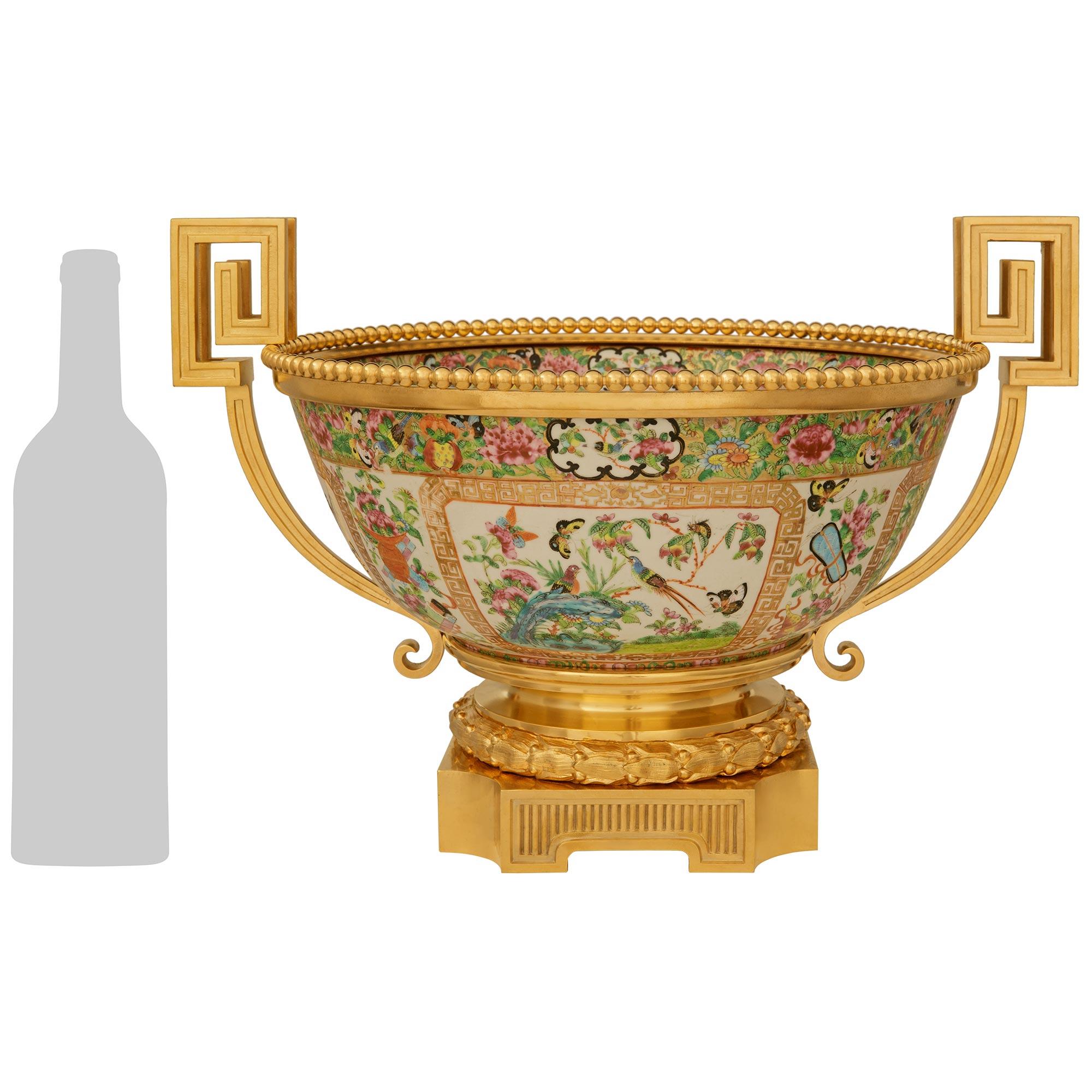 An impressive and most decorative French 19th century Belle Epoque Period Famille Rose Porcelain and Ormolu centerpiece urn. This stunning centerpiece is raised by a square Ormolu plinth with cut corners decorated on two sides by vertical ribbed