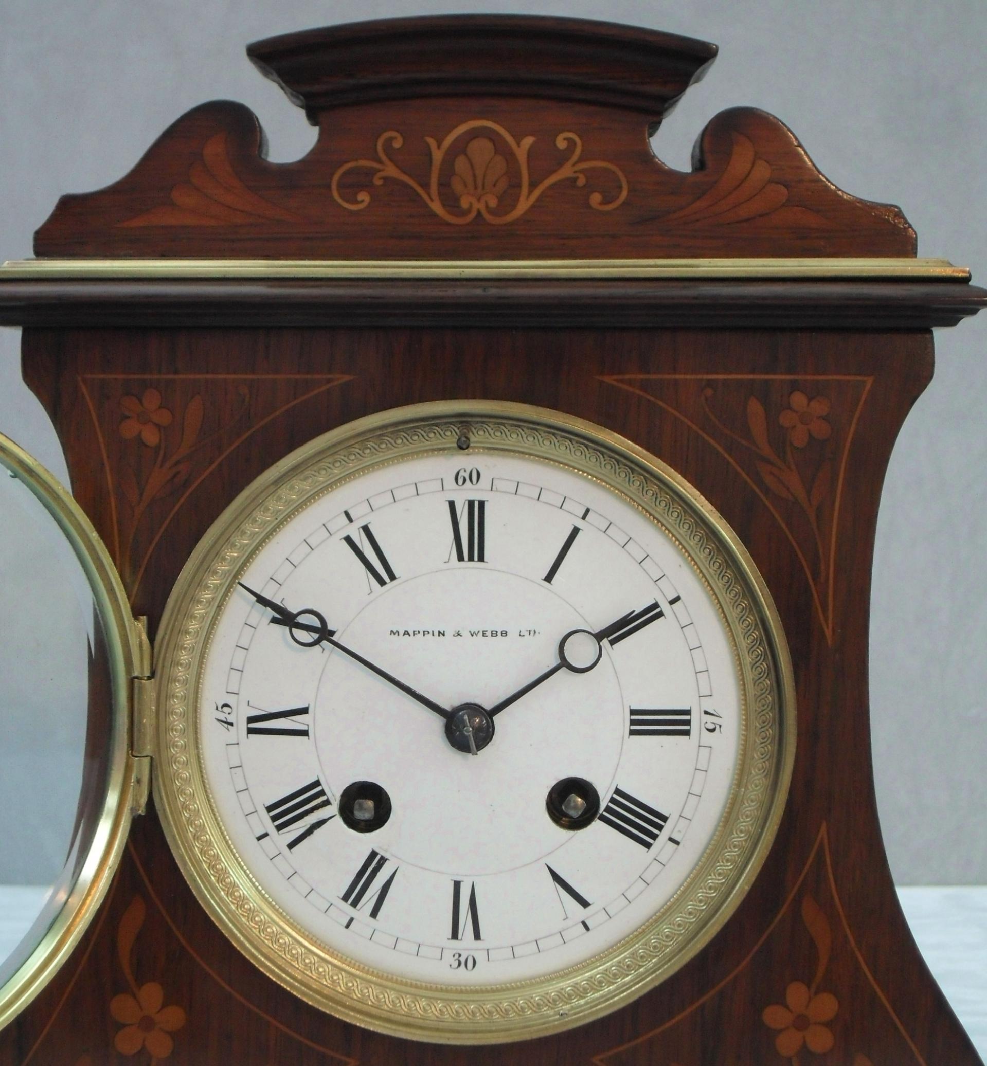 An extremely good quality French Belle Époque rosewood mantel clock with satinwood and boxwood floral inlay and stringing to the front of the case with brass moldings, feet and decorative bezel. The clock has a white enamel dial with eight day