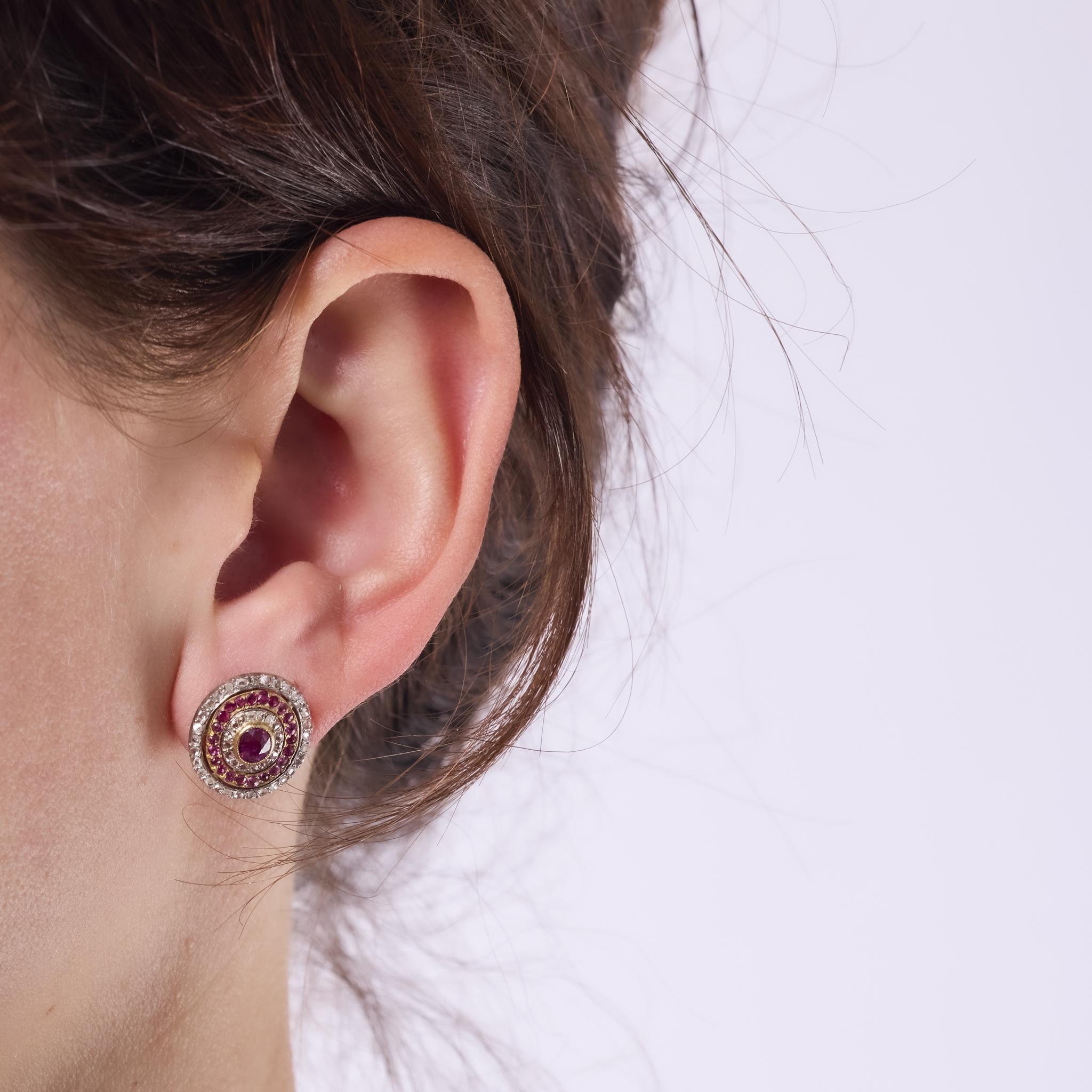 These exquisite French Belle Epoque earrings feature vivid oval rubies surrounded by rose cut diamonds and ruby accents. Crafted in 18k yellow gold with a platinum top, their graceful design and rich sparkle evoke the romance of early 20th-century