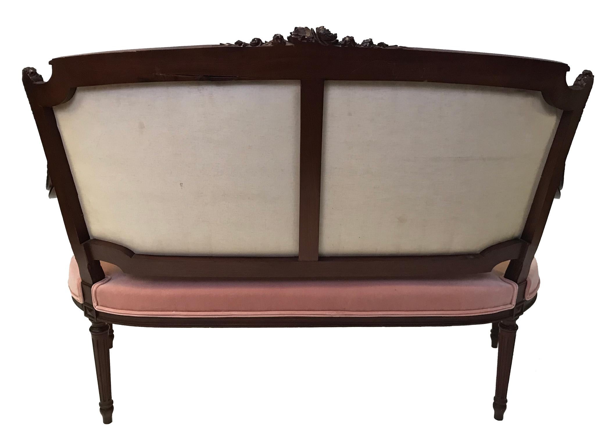 Beautifully carved mahogany with foliate and rose decoration, this striking Belle Époque settee is crafted in the typical manner of the Louis XVI taste during the fourth quarter of the 19th century. This has been recently upholstered in rose pink