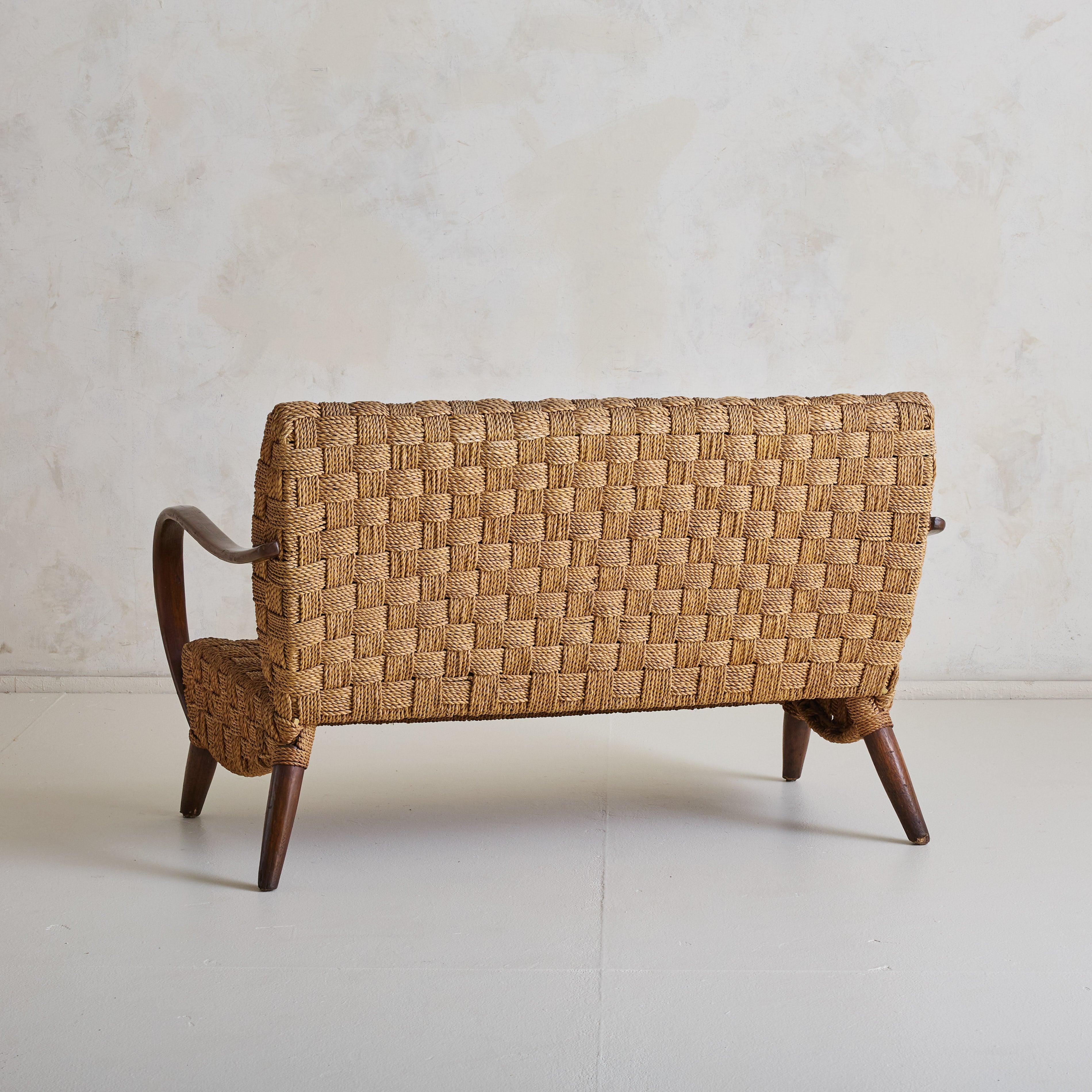 Un canapé français sculptural des années 1950, rappelant les designs d'Erich Dieckmann. Fabriquée en bois courbé richement teinté, cette pièce témoigne d'un savoir-faire exceptionnel et d'une grande attention aux détails. L'assise et le dossier sont