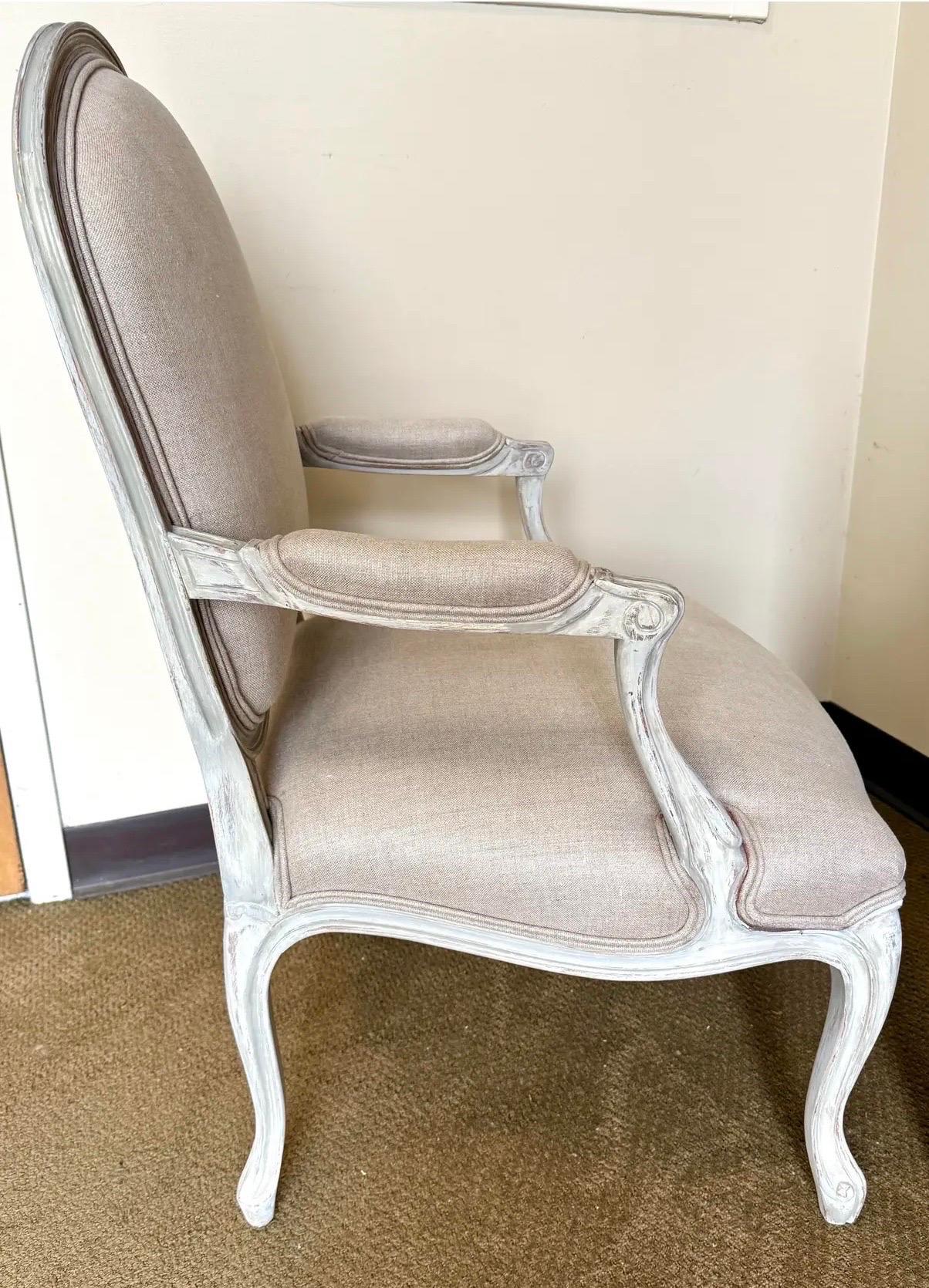 Chaise bergère sculptée à la main qui a été magnifiquement remise au goût du jour avec un revêtement en lin de première qualité de Brunschwig & Fils.  Le cadre sculpté à la main présente une finition peinte douce, mettant en valeur des courbes