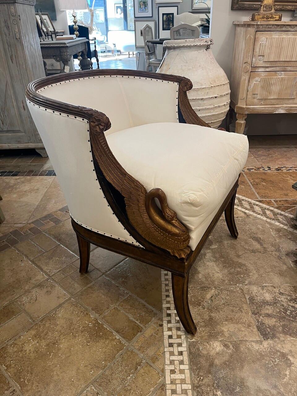 Revitalize your living space with a 20th Century French Bergere Chair adorned with stunning gilt carved swans and fresh upholstery. This piece seamlessly blends classic French craftsmanship with modern comfort, adding a touch of sophistication to