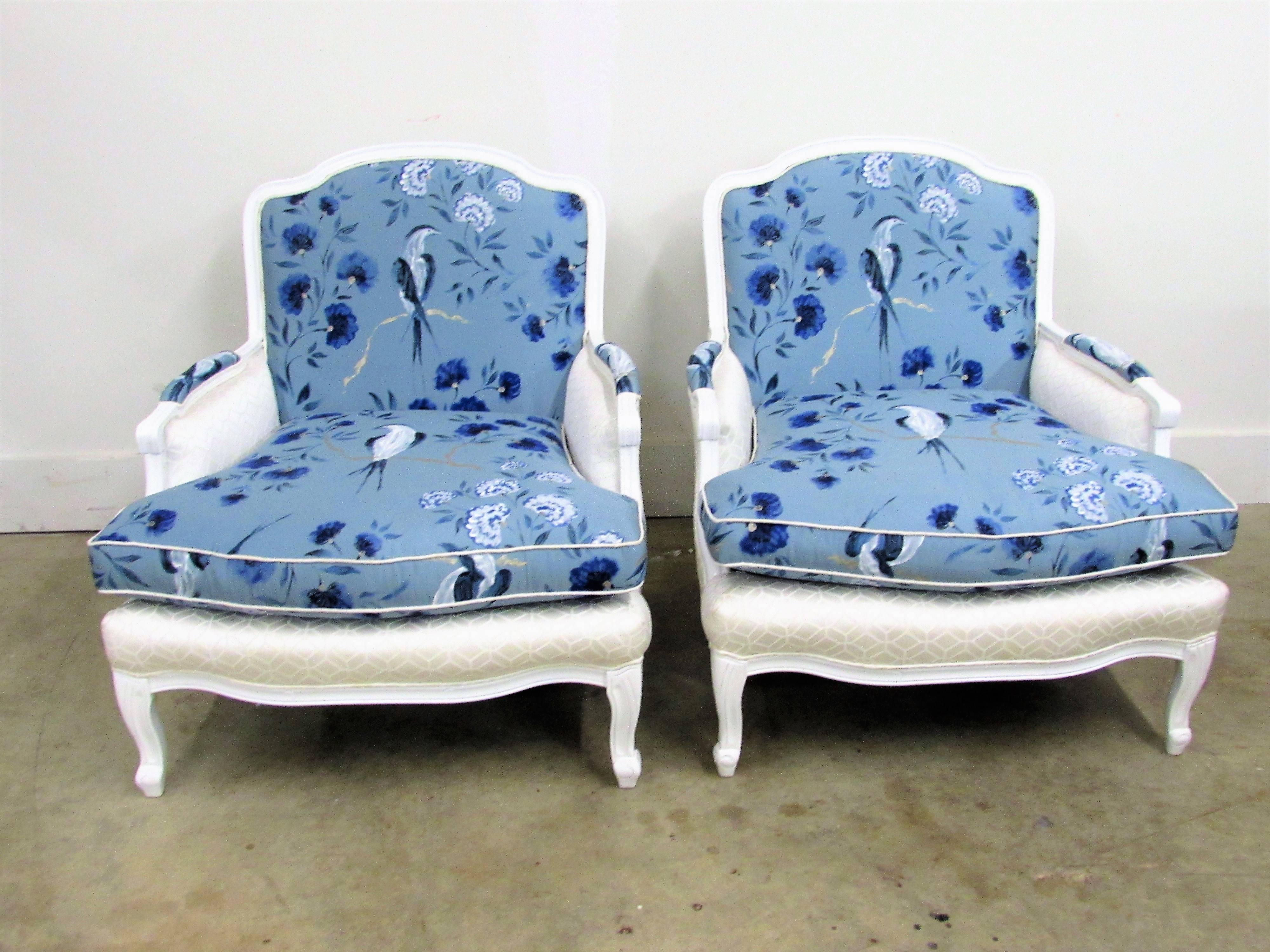 Elegant pair of French mahogany Bergère armchairs in white lacquer and designers Guild Jacaranda-Indigo 100% silk fabric with elegant birds perching on delightfully hand-painted branches of oriental blossoms in rich vibrant colors in blue and white,