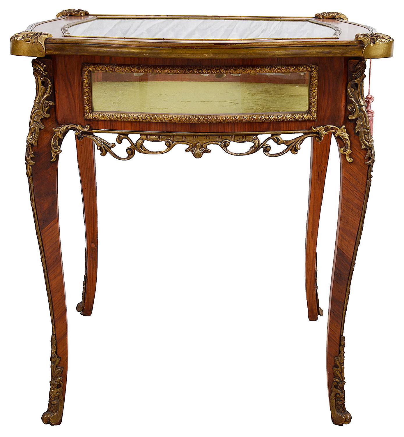 A good quality French mahogany, ormolu-mounted bijouterie table, having glazed sides and top, a hinged top, opening to reveal a silk lined display compartment, raised on elegant cabriole legs.