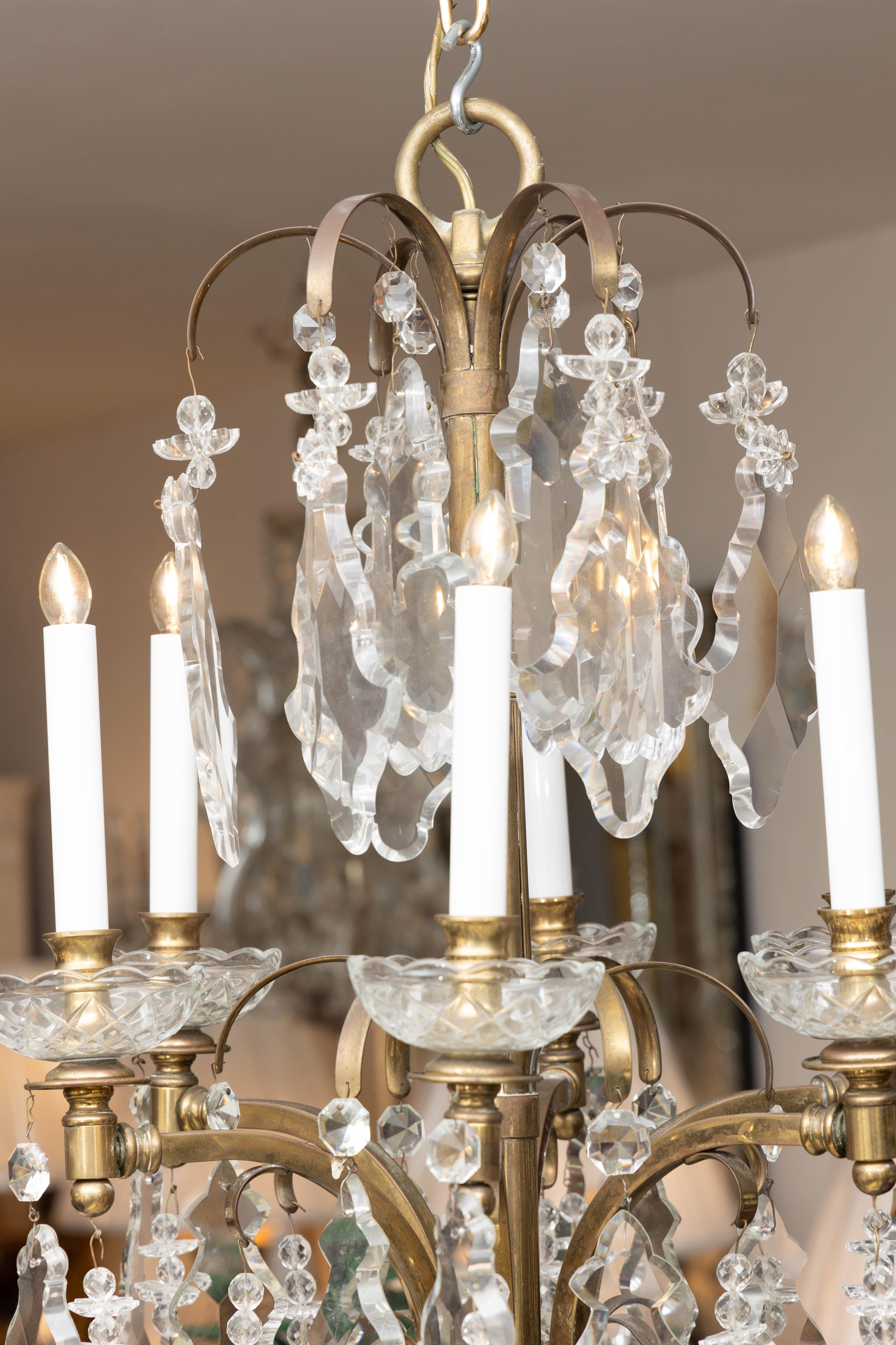 This is a beautiful early 20th century French brass chandelier strung throughout with exquisite shaped crystal prisms.