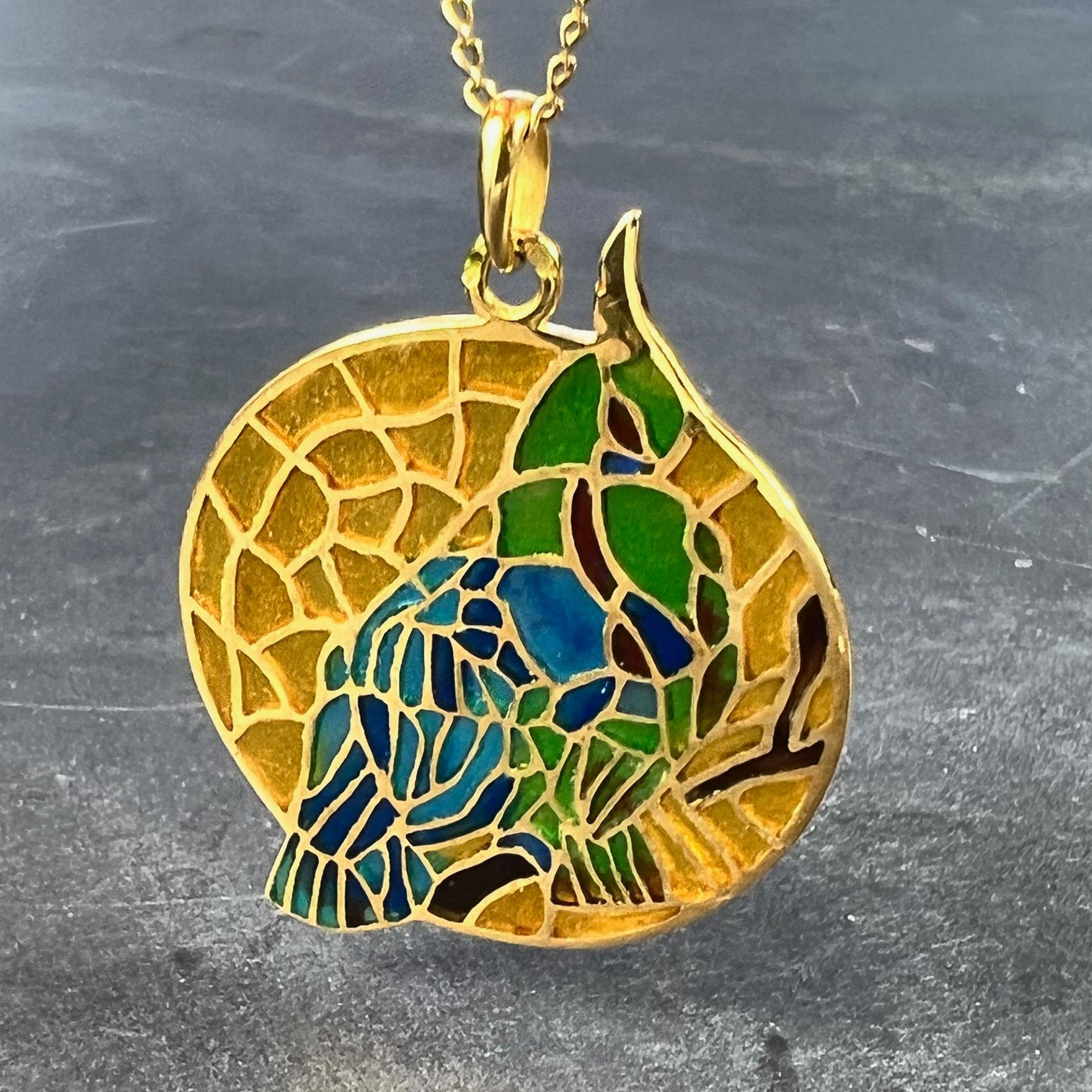 A French 18 karat (18K) yellow gold charm pendant designed as a round medal depicting a blue and green bird on a yellow background in plique-a-jour enamel. Stamped with the eagle’s head for 18 karat gold and French manufacture, and a partial maker's