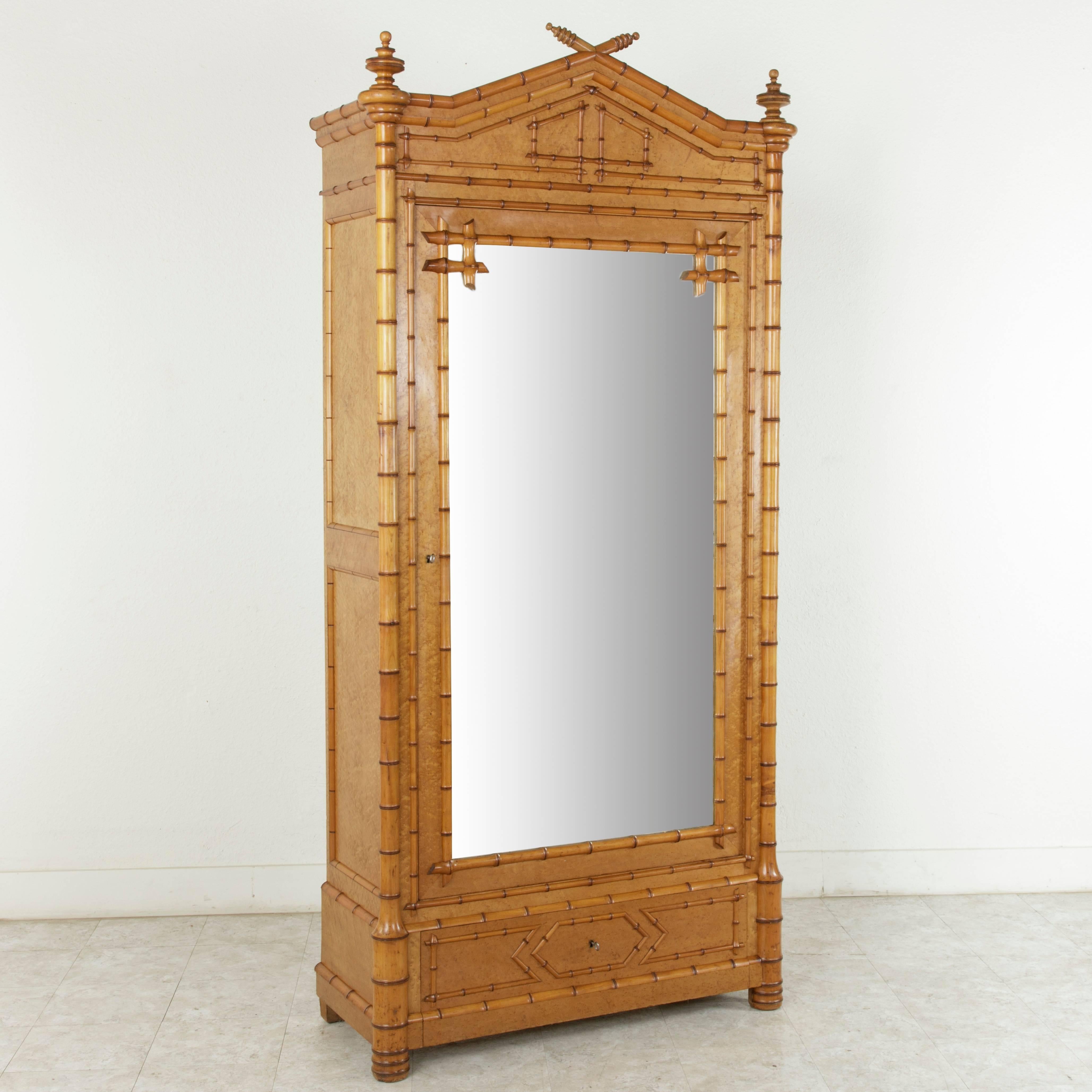 This faux bamboo armoire made of cherrywood and bird's-eye maple is in absolutely pristine condition. Finely detailed bamboo pieces, harmoniously laid in a uniform pattern, blend with the handsome geometric motif in the upper pediment and lower