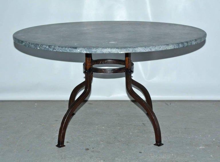 Indoor or outdoor French bistro style garden coffee table with round stone top married to a bronze colored wrought iron base that is secured by gracefully arched legs and round stretcher. Top and base can be sold separately. Top: 900/base: 1900.