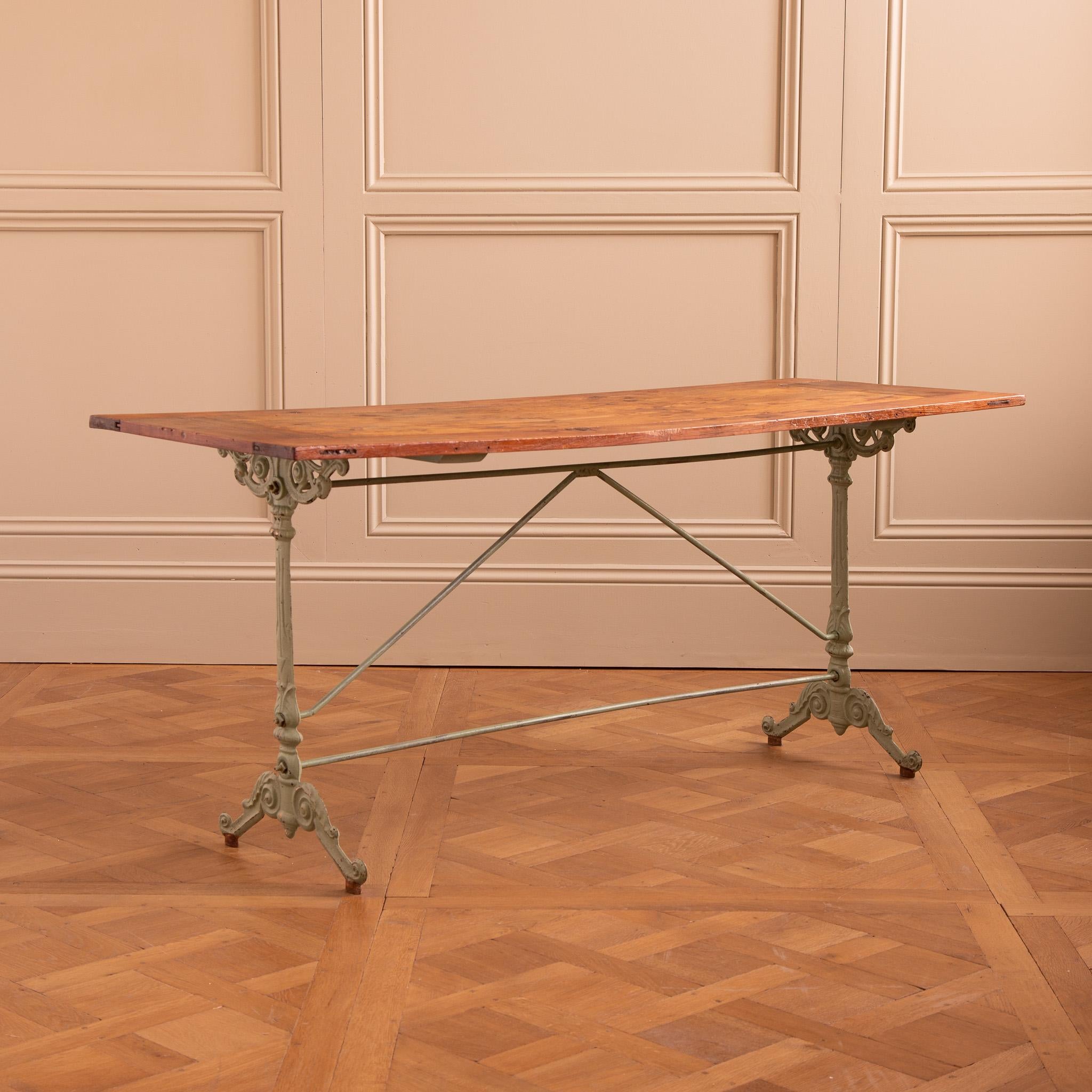 A French bistro cafe table from the Early 1900's with a decoratively cast iron base painted in a typical Art deco green. The table top is a nicely aged, old Douglas wood with lots of character. The proportions have a slimline width-to-length ratio