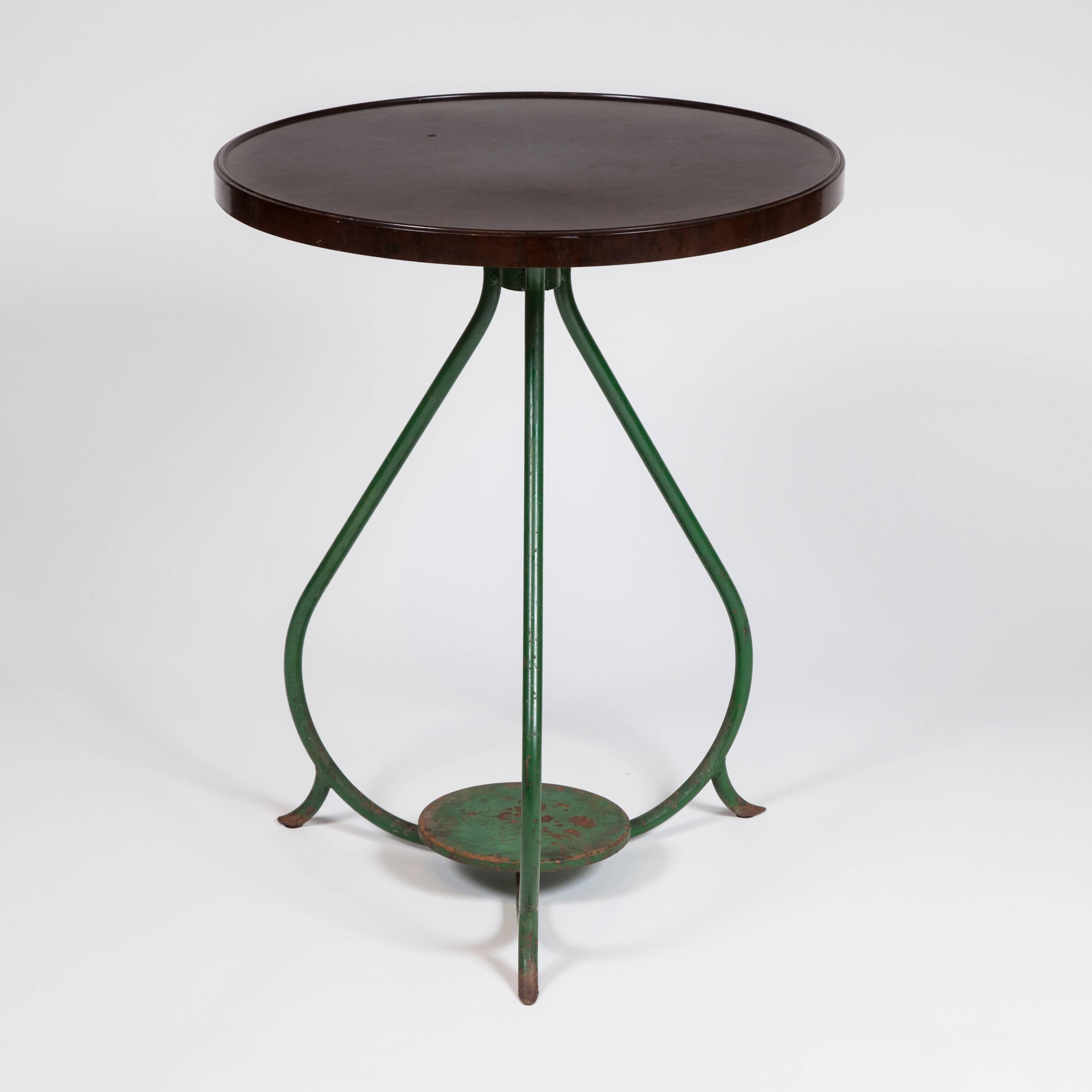 A French bistro table with circular bakelite top and green painted iron legs.