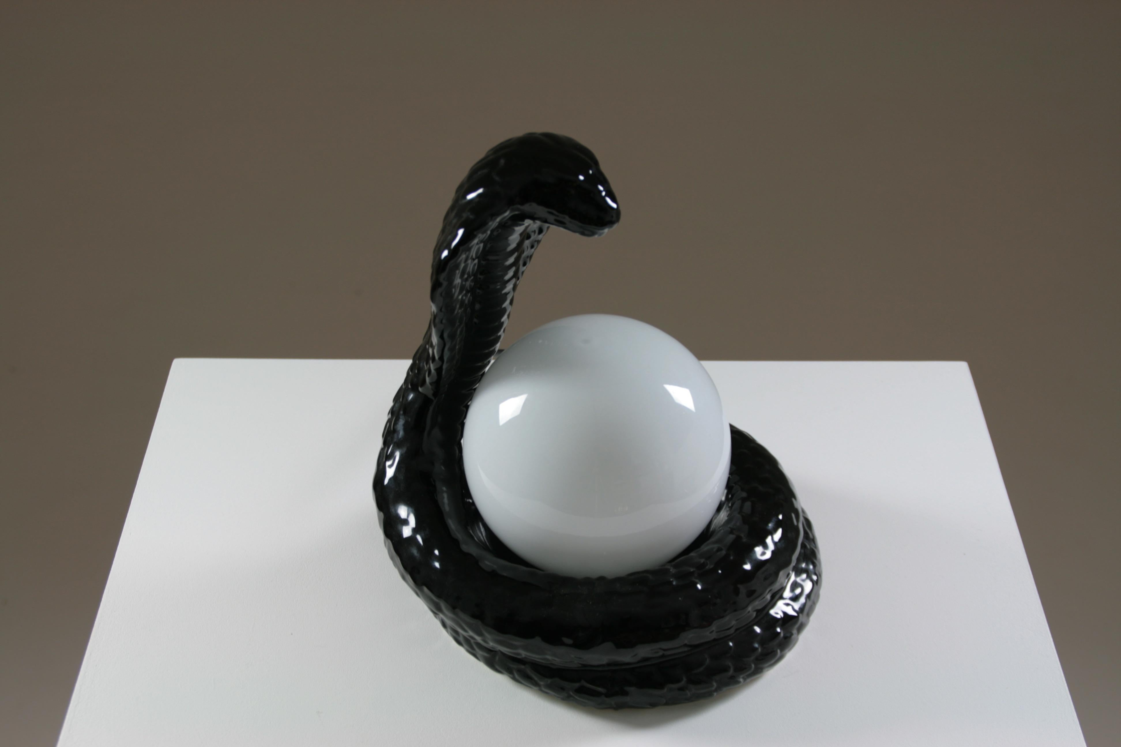 “Cobra” model table lamp in black ceramic, produced in France in the 1980s. Opaline glass globe.
Very good condition.