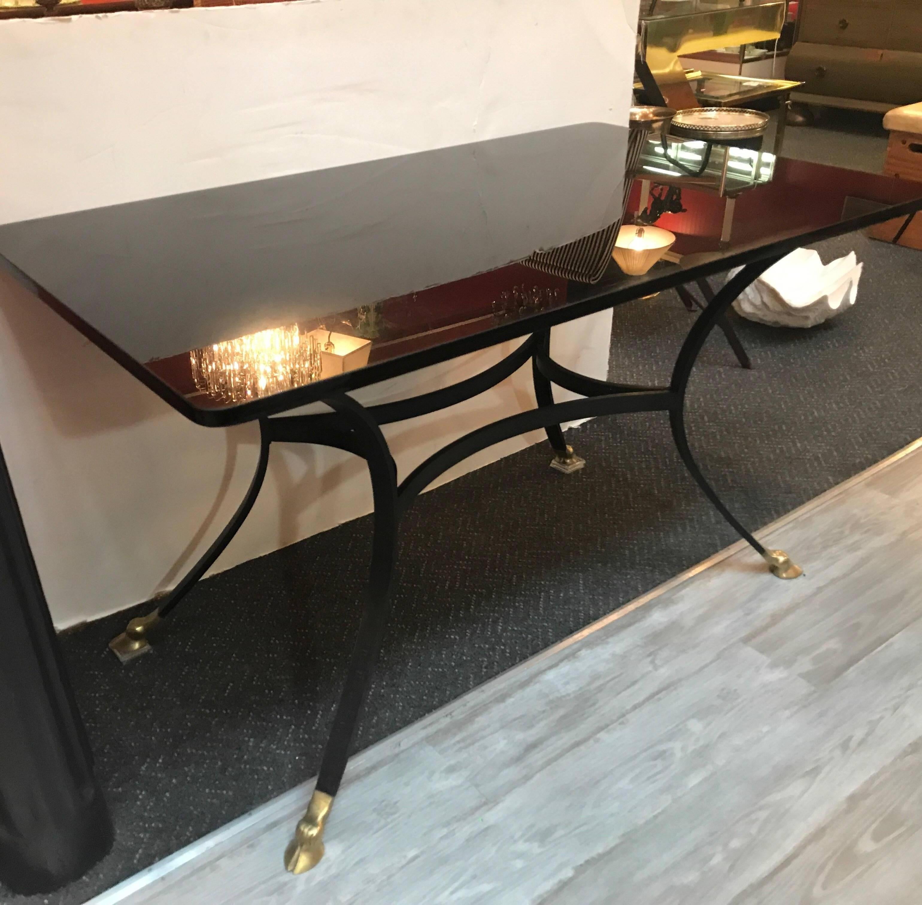 A French writing desk with a thick black glass top. The iron base with cast bronzed hoof feet in the manner of LaBarge. The top is original with signs of surface use.