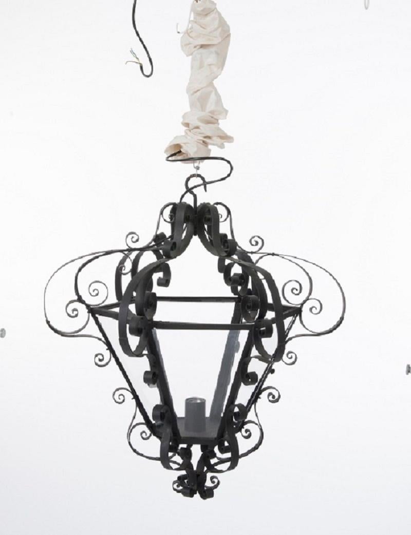 French lantern out of iron, glass shades circa 1940

Black, conical, hexagonal body with sweeping exterior decoration out of metal straps.
4 glass panes and 1 socket
Body dimensions 48cm
Body dimensions with decoration 68cm.
