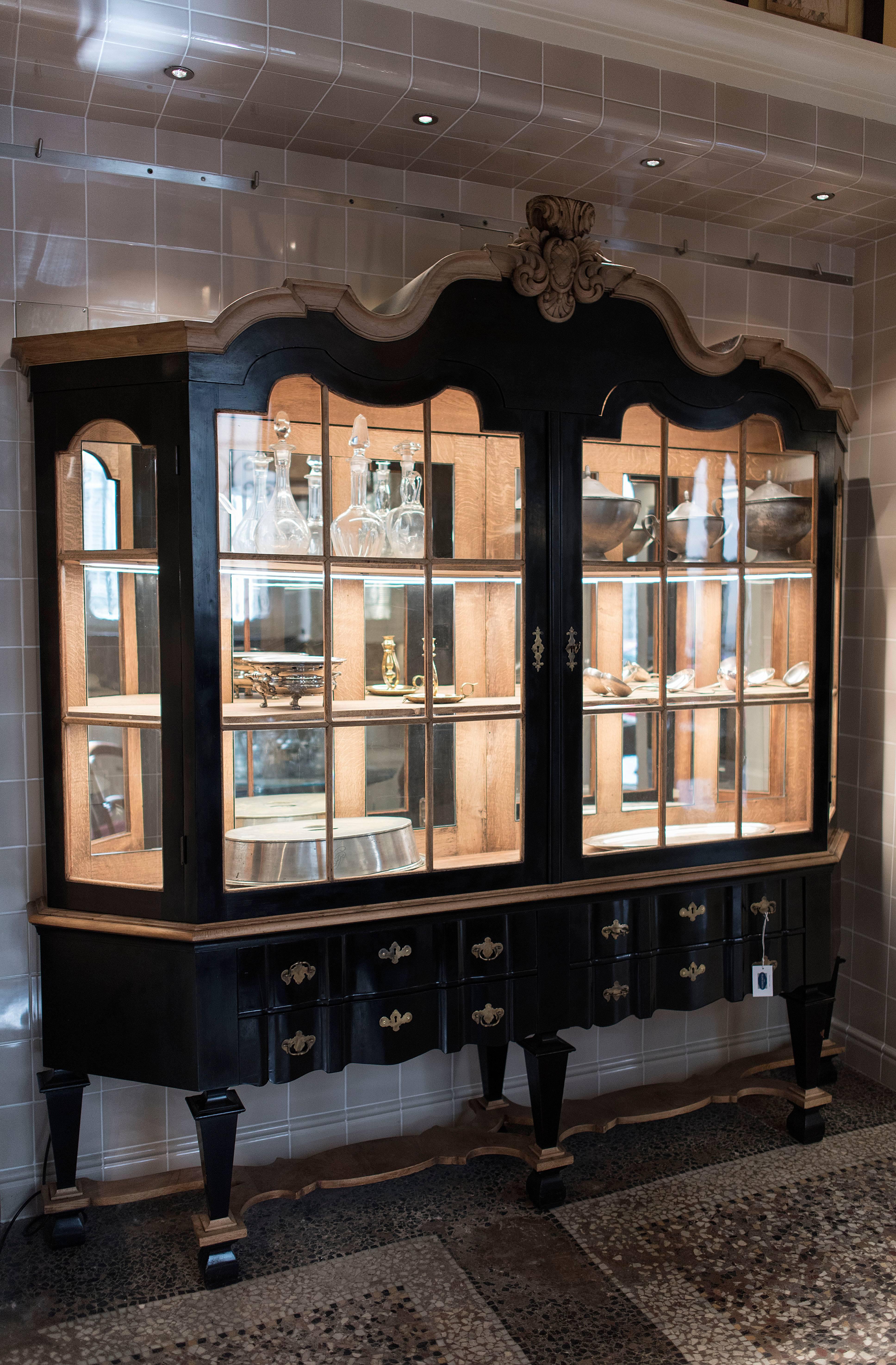 French early 20th century black painted double body wooden cupboard with drawers and shutters. The cupboard has mirrors on the background and accessories in solid brass.