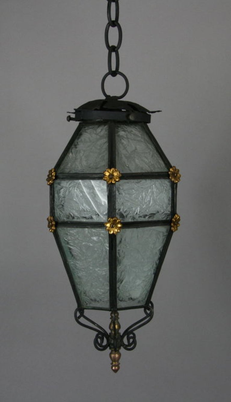 A blackened multi-sided patterned glass set in a finely iron frame embellished wit gilt rosettes. Lantern 14 inches H for 6.5 inches W, One Edison -base 100watt bulb.