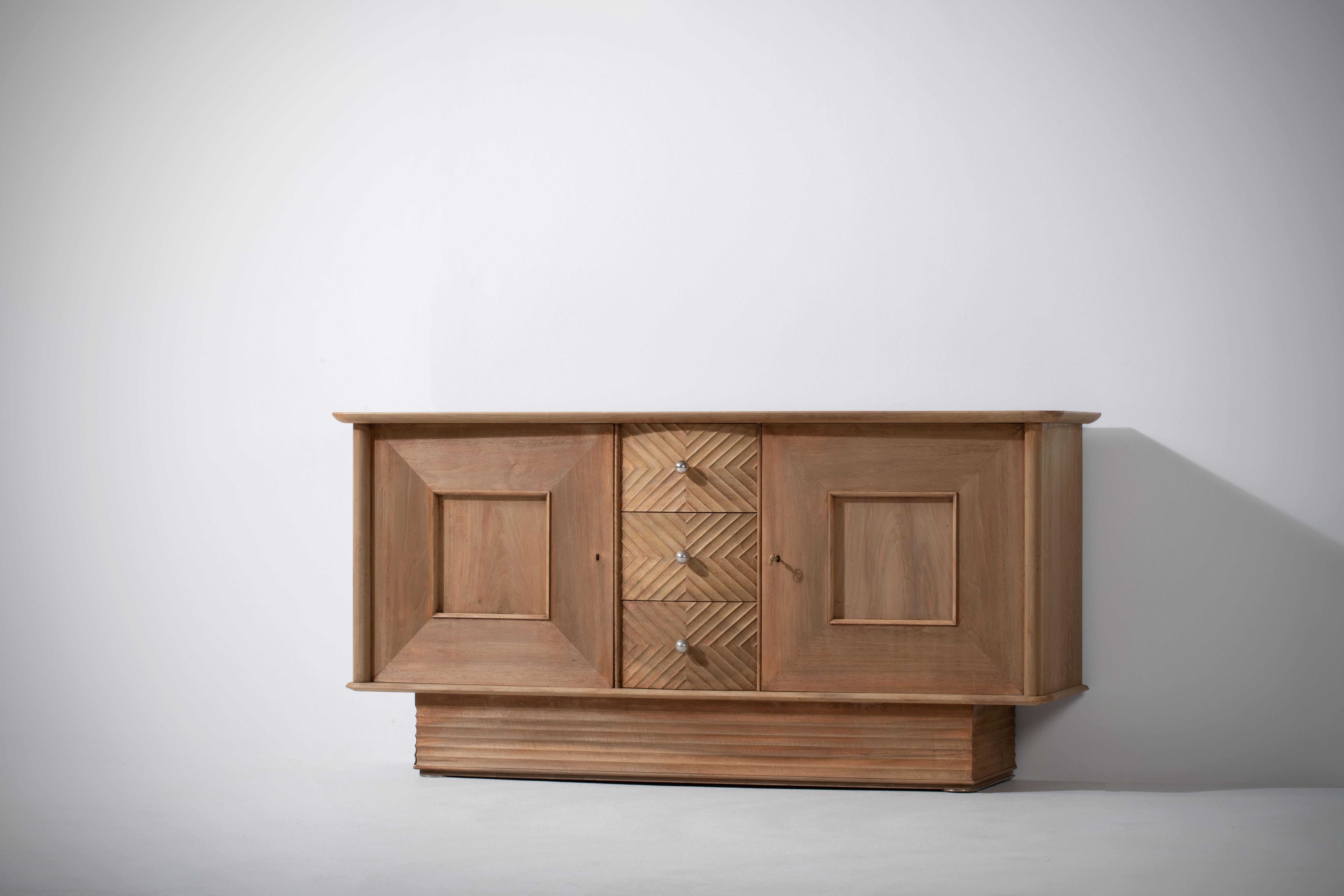 Elegant Credenza, solid oak, France, reminiscent of the work of Jean Royère, 1940s.
Large Art Deco Brutalist sideboard. 
The credenza consists of two laterals storage facilities and central drawers covered with geometrical reliefs. 
Good