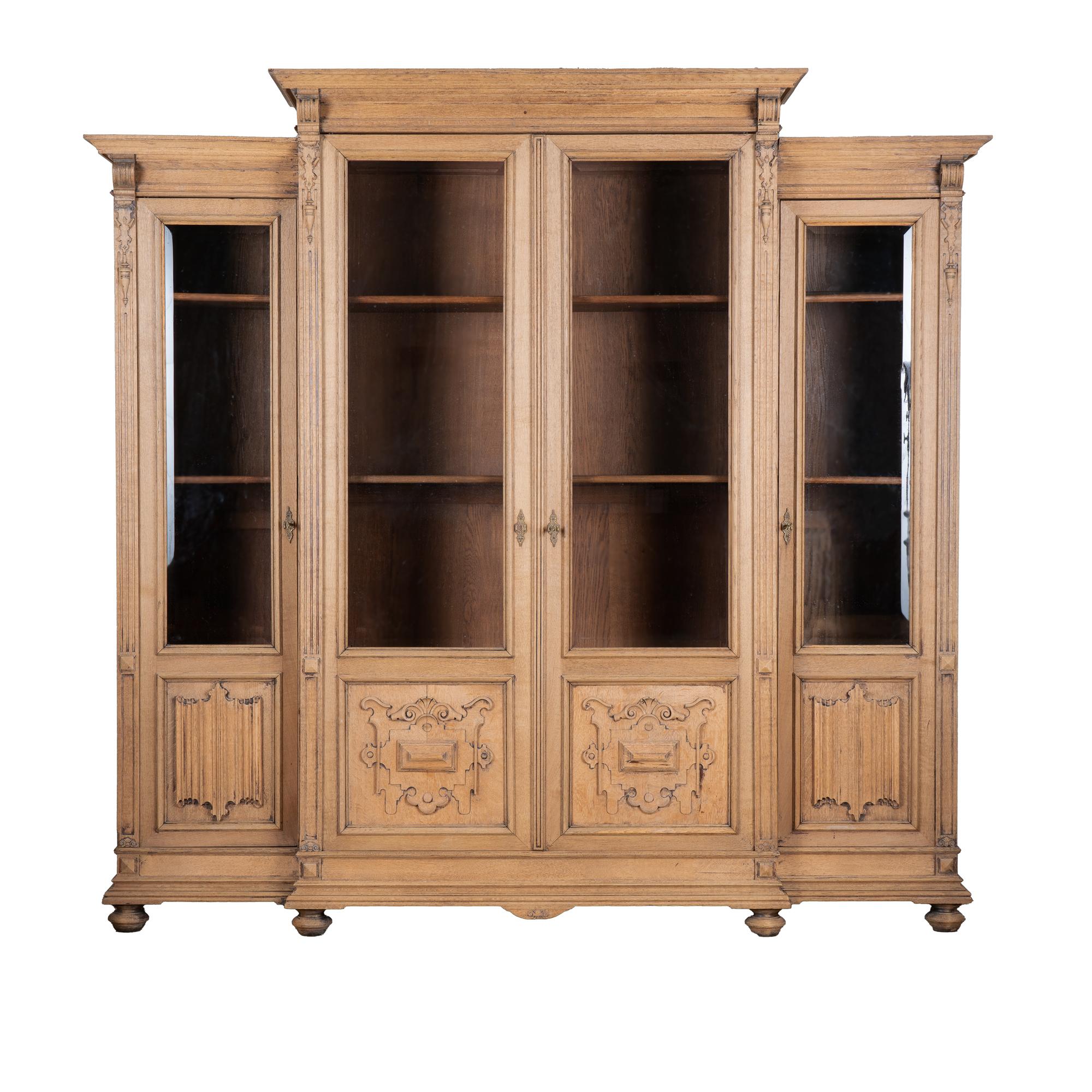 The elongated four beveled glass doors are complimented by the carved details in this statuesque bookcase from France.
The oak has been bleached, giving it a fresh look for today's modern home while highlighting the attractive French country
