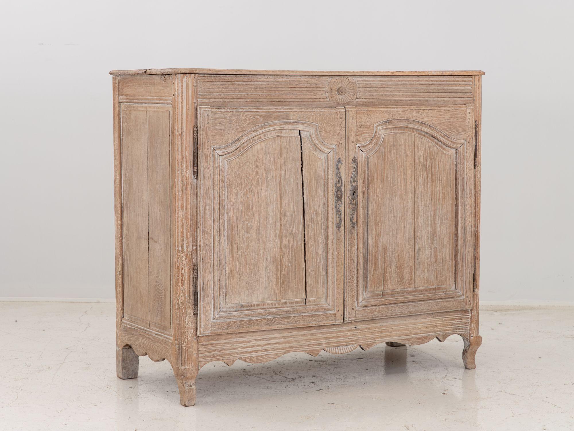 A mid 19th century French buffet. This buffet is oak and has been bleached and white washed for a modern aesthetic. Behind the two doors are a shelf with two narrow drawers that separate the upper and lower compartments providing ample storage. Some