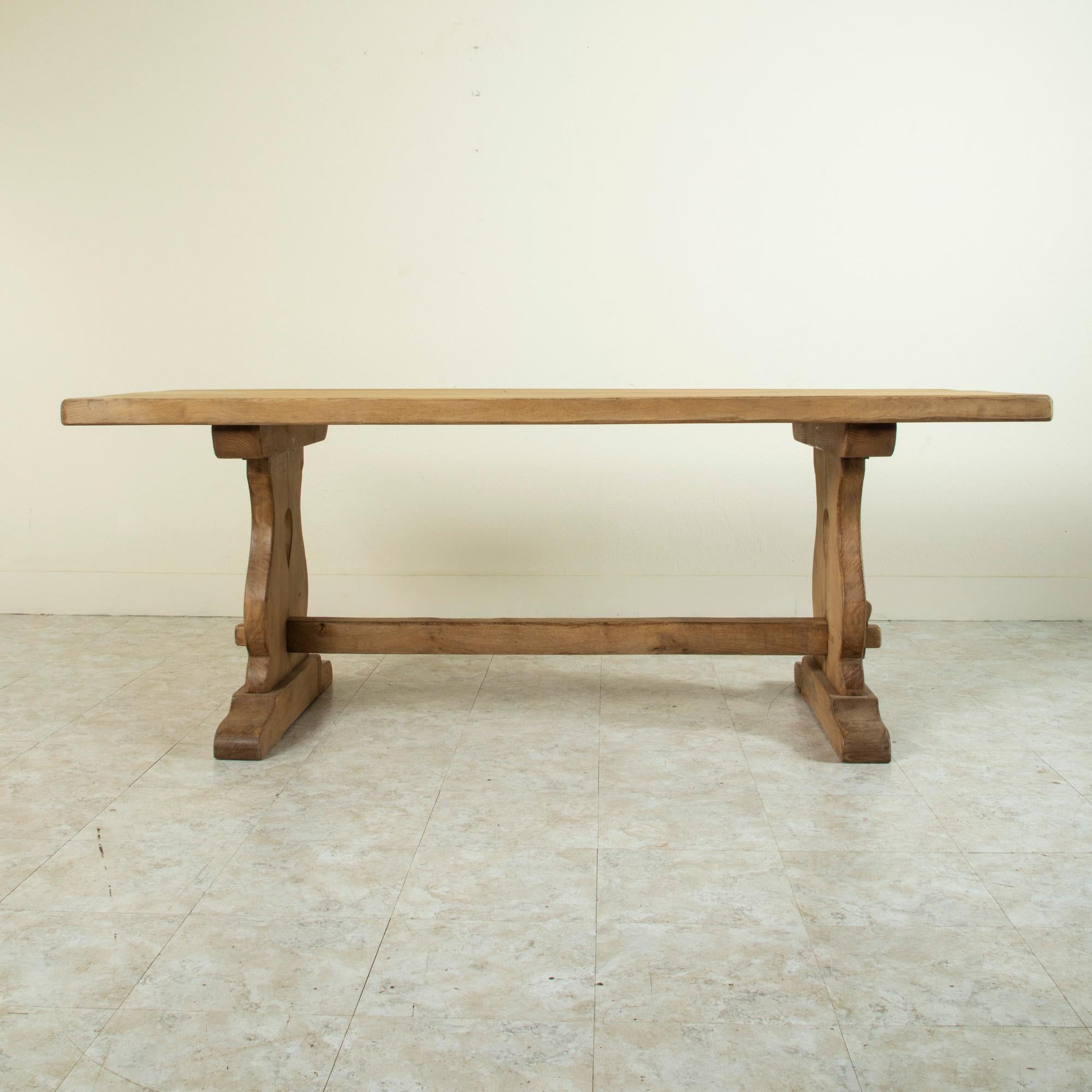From the region of Normandy, France, this artisan-made oak monastery table or dining table from the turn of the twentieth century features a two-inch thick top constructed of seven planks of wood. Resting on a sturdy trestle base constructed using