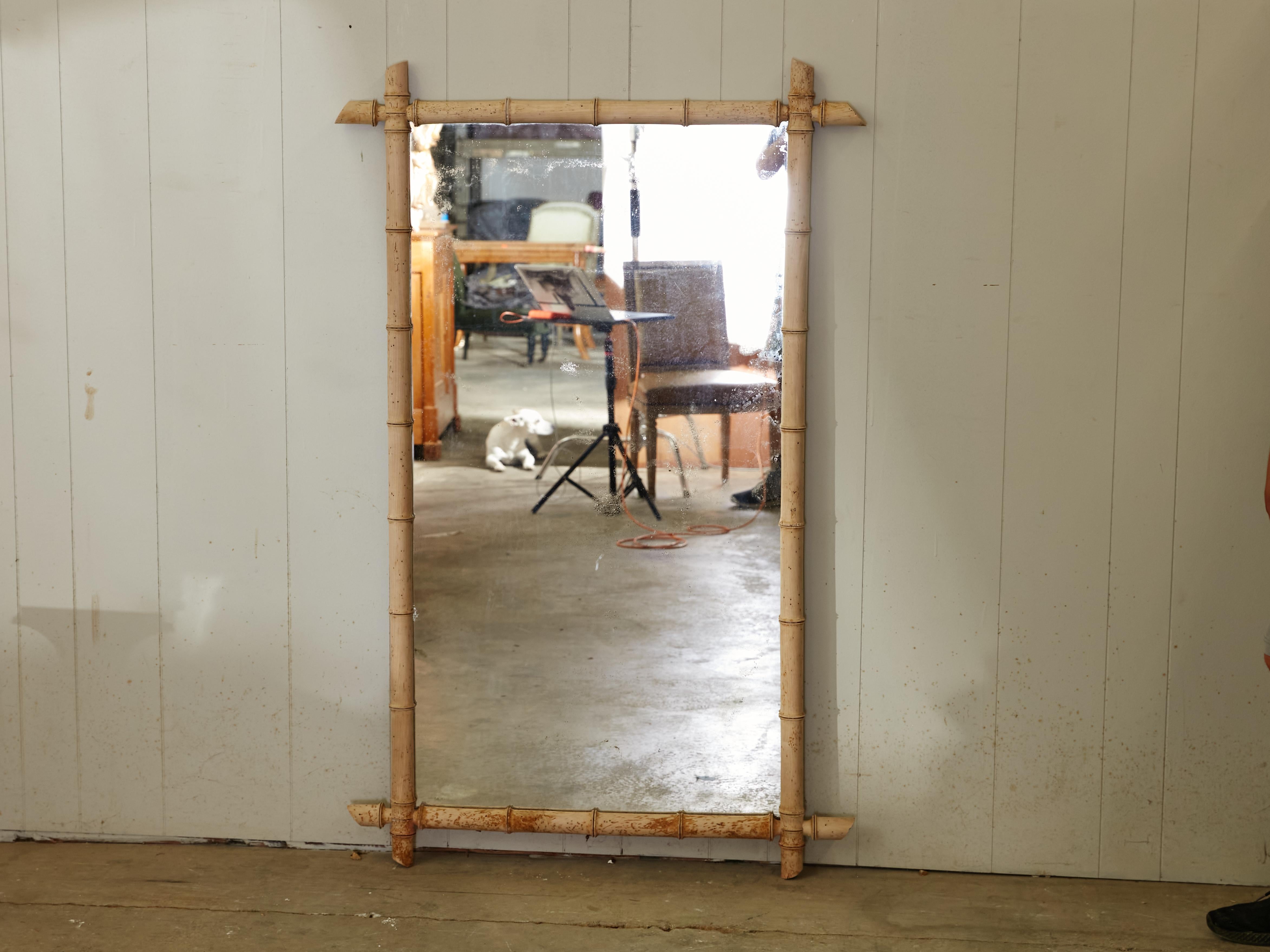 A slender French rustic Turn of the Century rectangular faux-bamboo bleached walnut mirror from the early 20th century, with intersecting corners, slanted accents and nicely weathered patina. Created in France at the Turn of the Century which saw