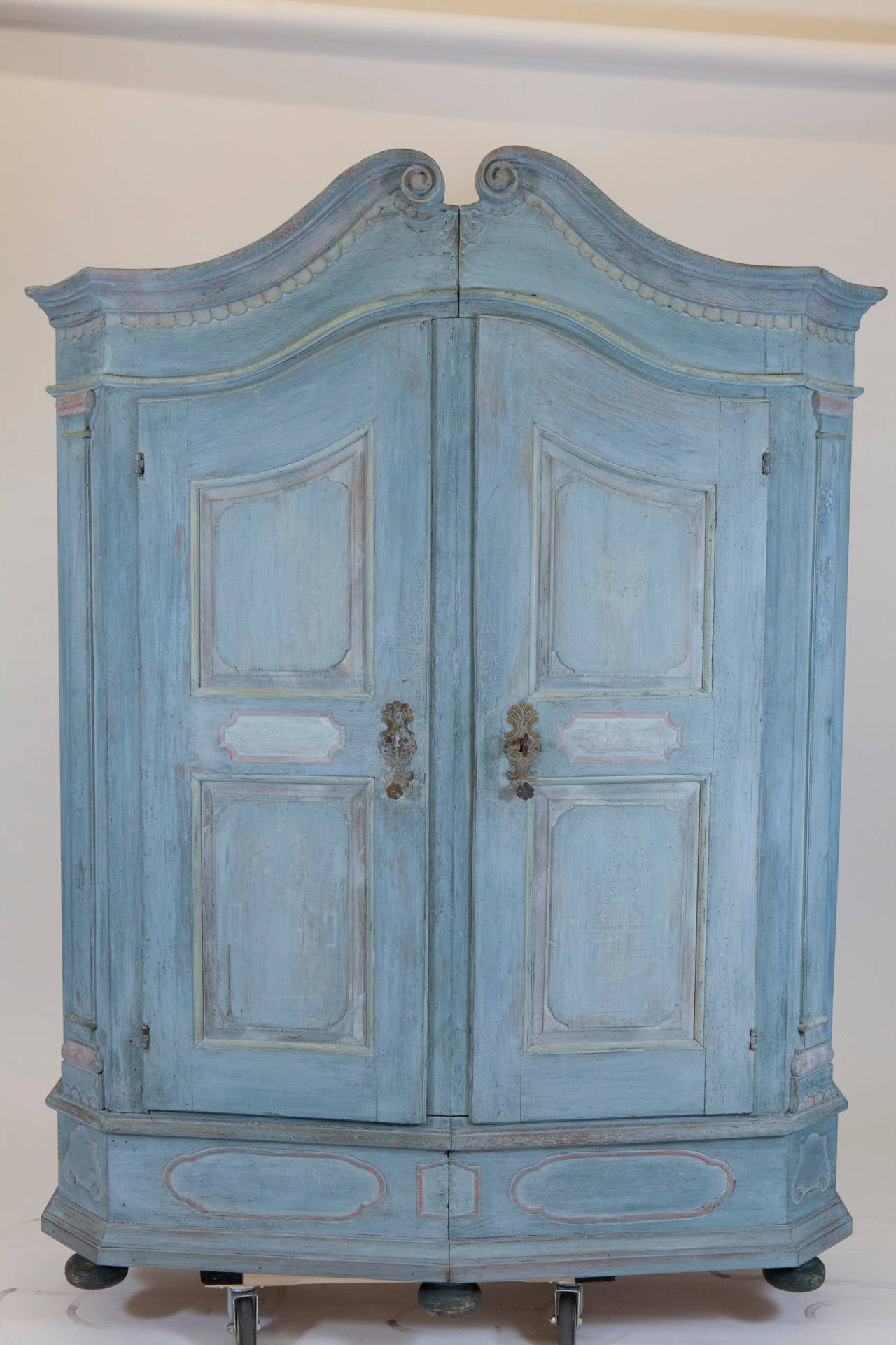 A light blue painted armoire from the 18th century. Great color and patina. Older painted and textural details are faintly visible under blue wash color. Piece has two doors with working key and brass handles. Inside, each side has three shelves