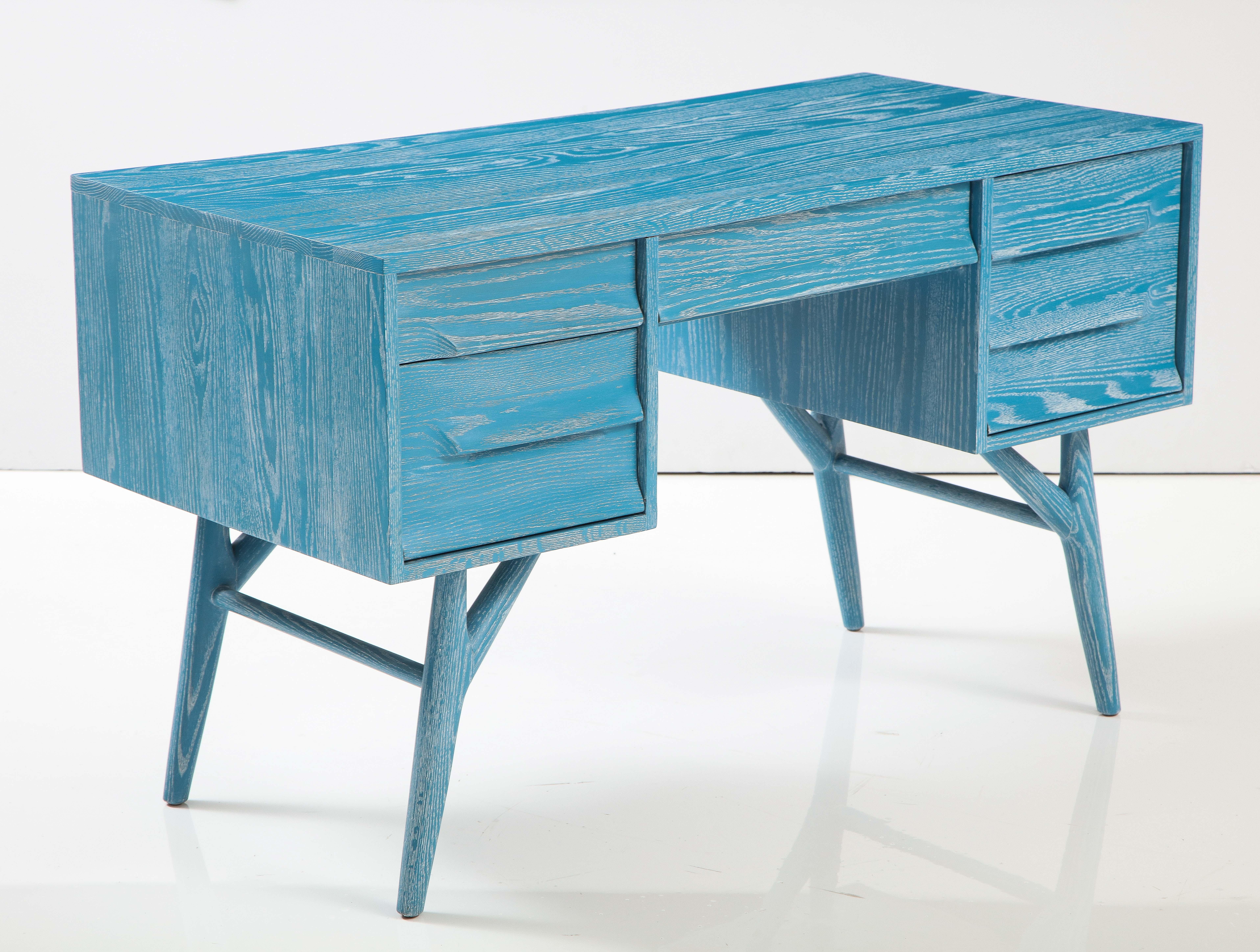 Custom mid century desk featuring a custom cerused oak finish in a French Blue accented with white to accent the grain. Desk has a central pull out drawer and 3 ample side compartments.