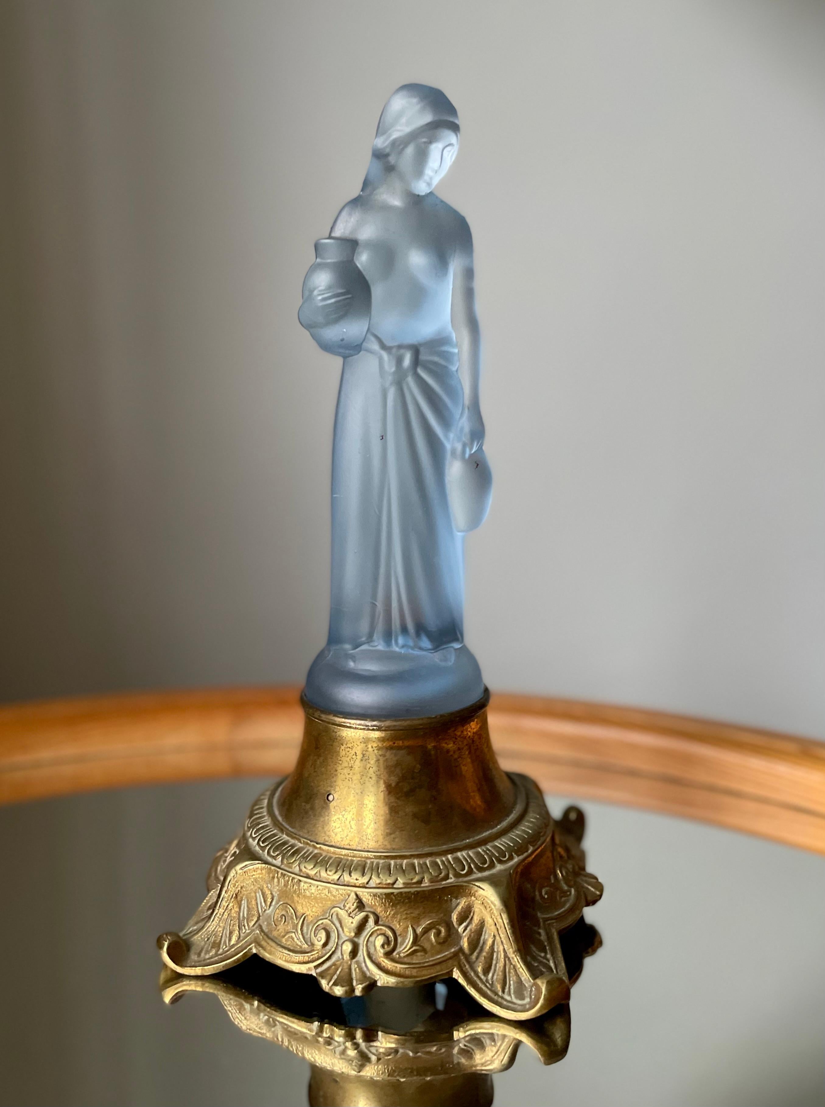 Light blue translucent frosted art glass shaped as a slender, long-haired woman wearing a long skirt and carrying a large jug in each hand. Mounted on decorative golden metal base on four feet.
Beautiful art nouveau piece in great vintage condition.