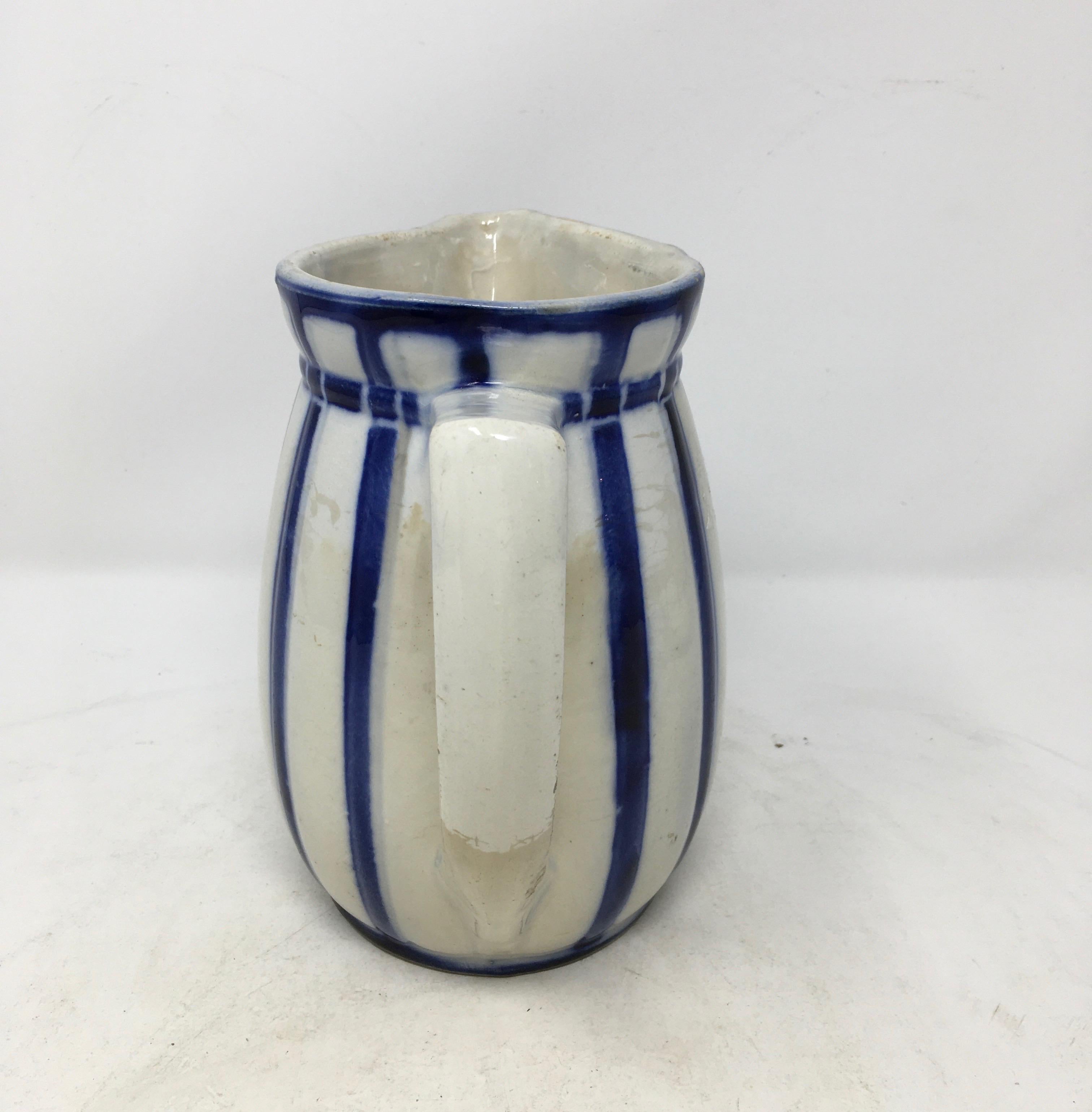 This graceful white pitcher has a slightly ridged body, accented by cobalt blue stripes at about one inch intervals. Perfect for milk, or lovely with a flower, this would be a pleasant addition to any kitchen.

This piece weighs 1.5 lbs.