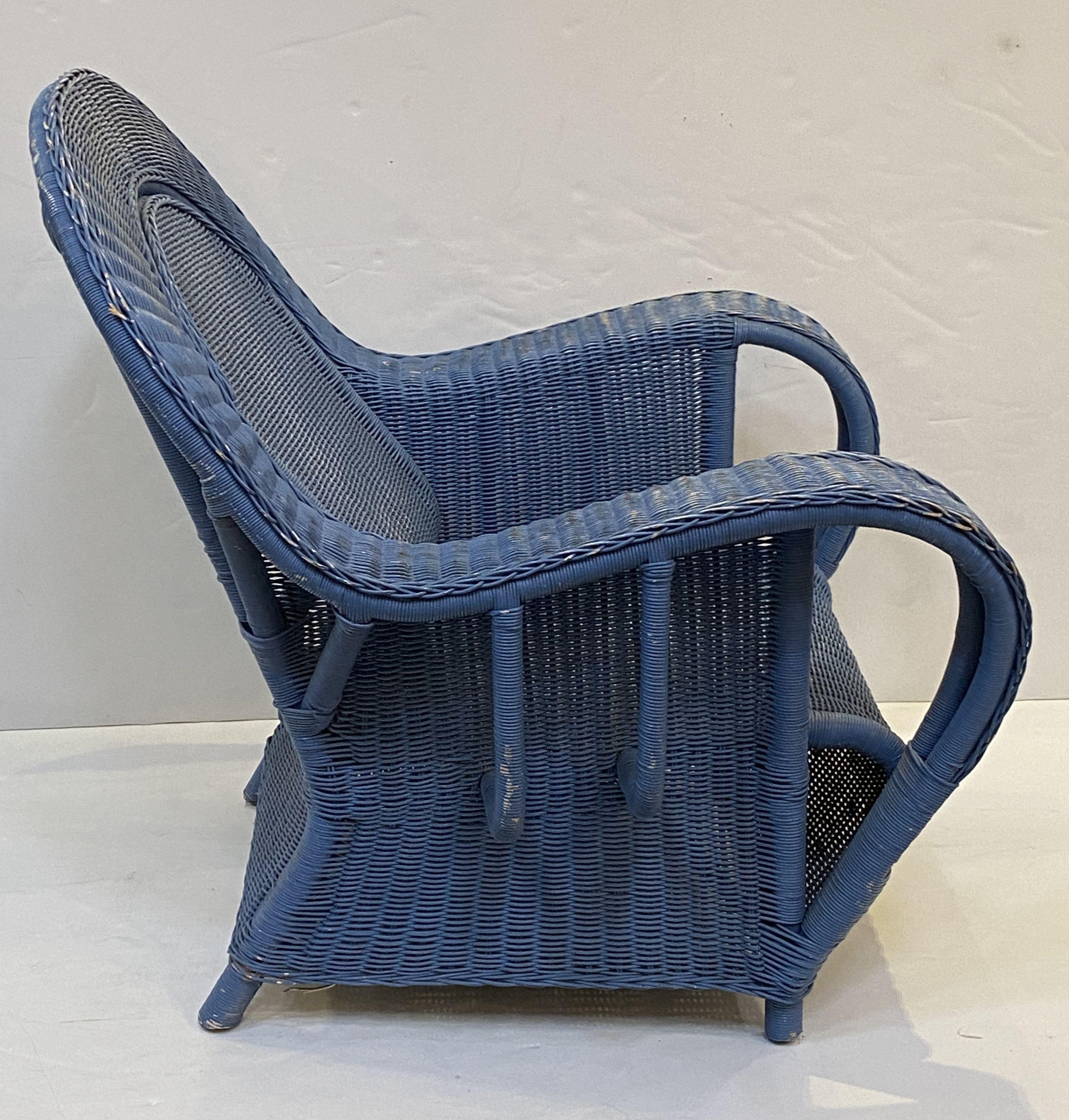 A fine pair of French woven wicker lounge armchairs in the Art Deco style, each chair featuring a beautiful faded blue painted exterior, with scroll back and arms, comfortable seat, and resting on a four-legged frame.

Overall dimensions:
H 37 in
W